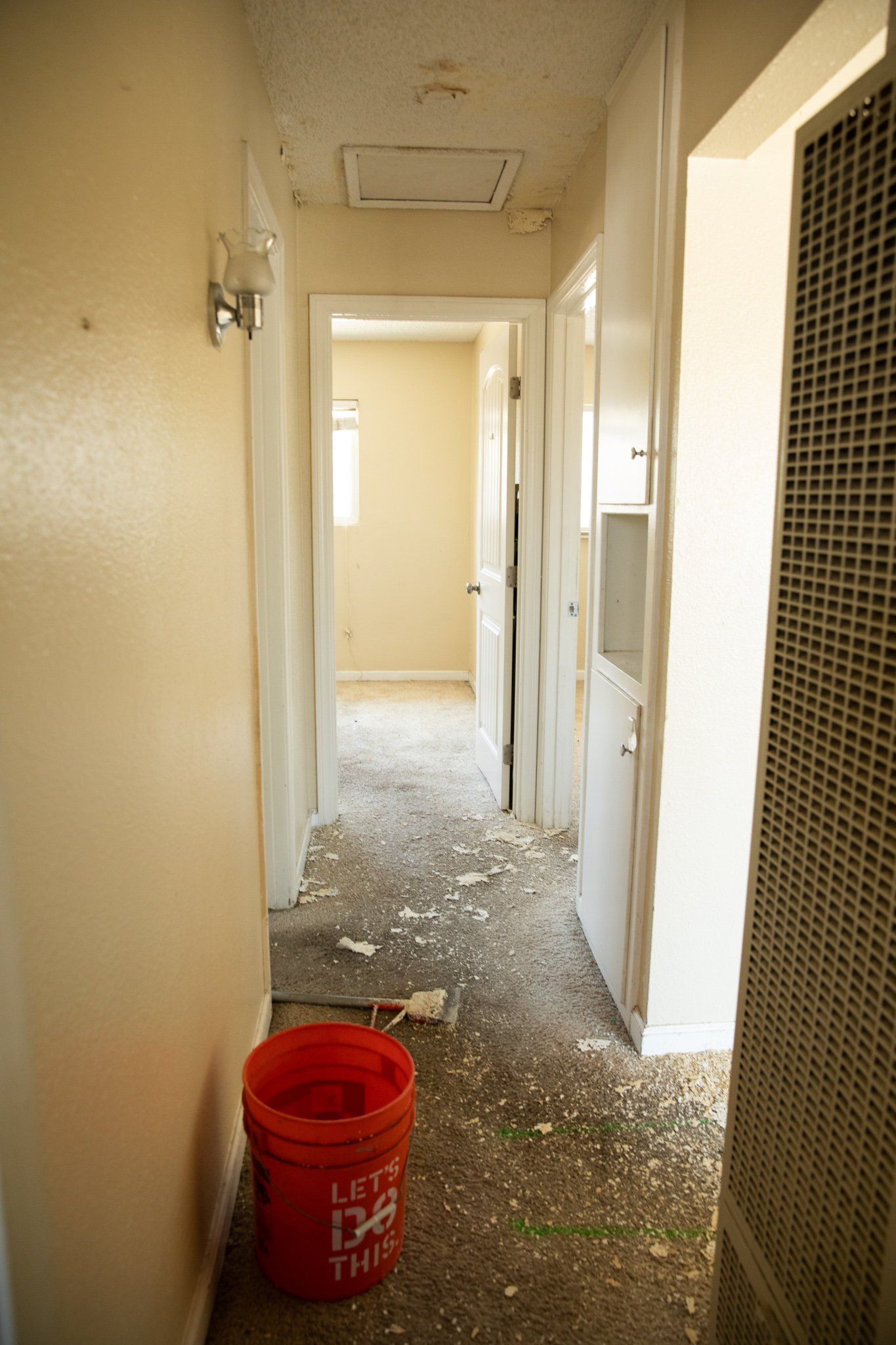 A red bucket in a hallway that says cat litter