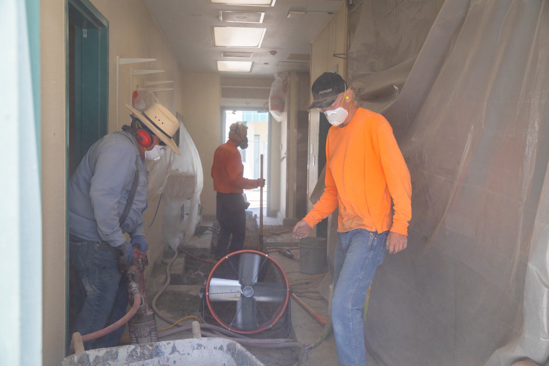 Two men wearing masks are standing in a hallway.