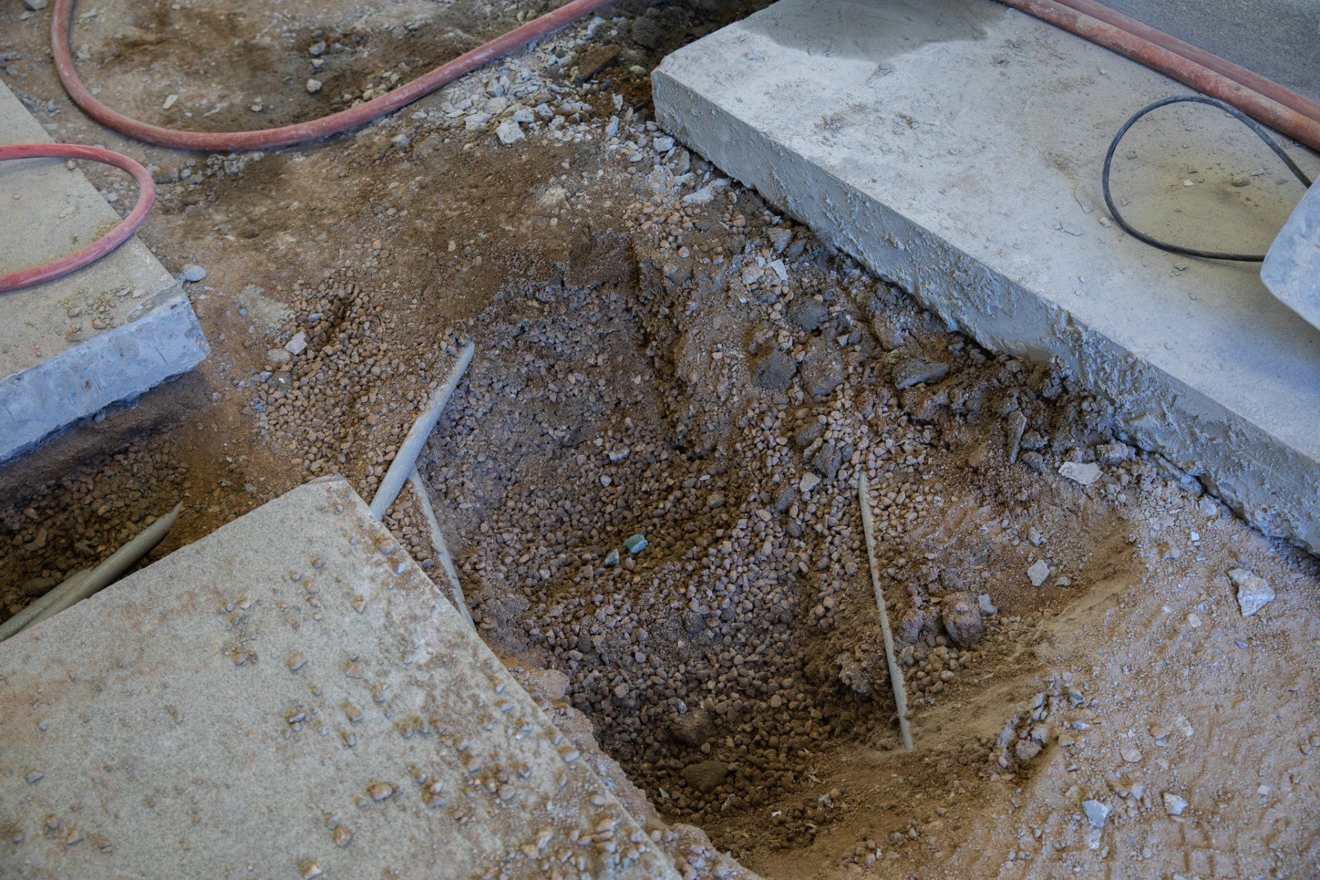 A person is digging a hole in the ground next to a concrete slab.