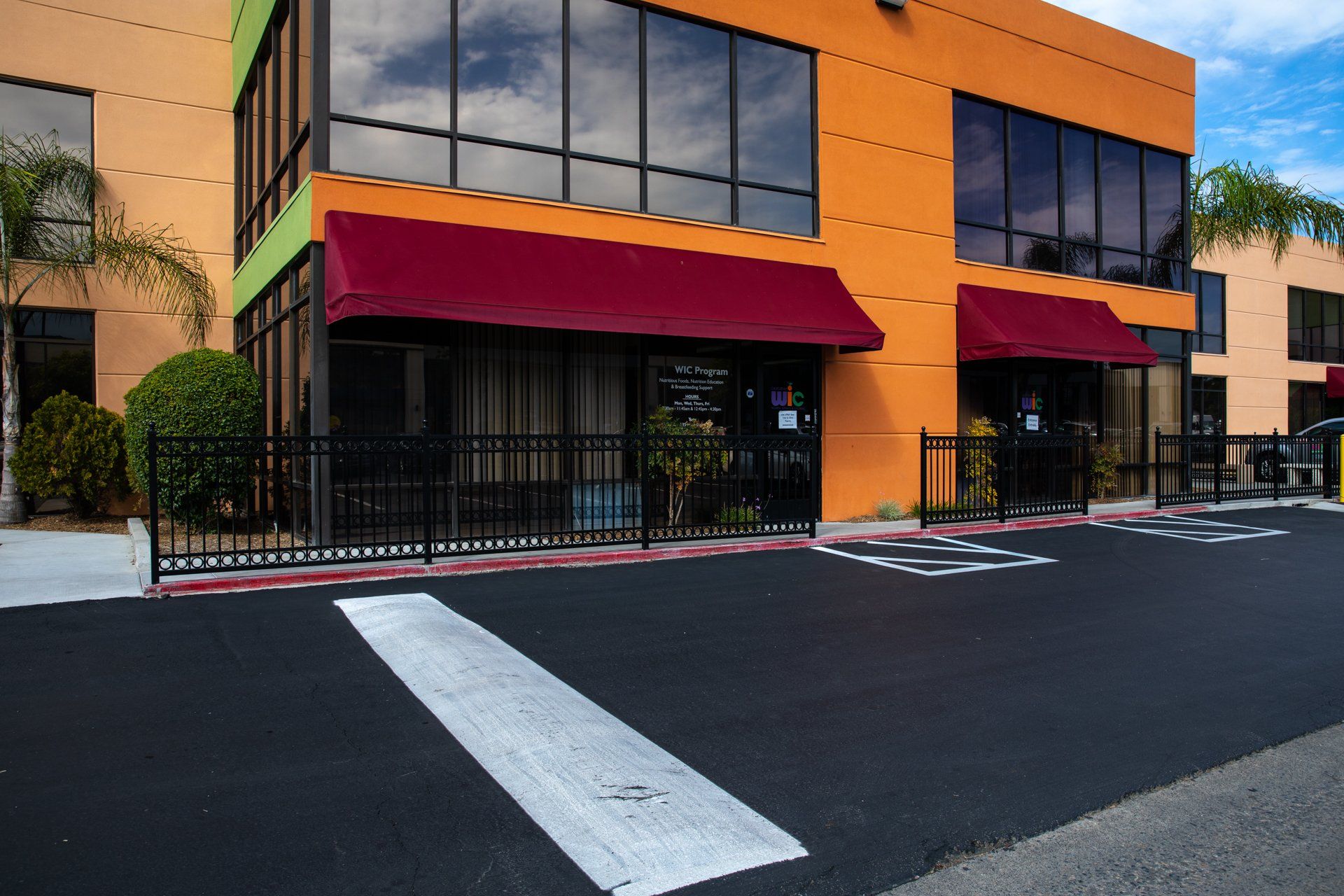 A large orange building with a red awning and a parking lot in front of it