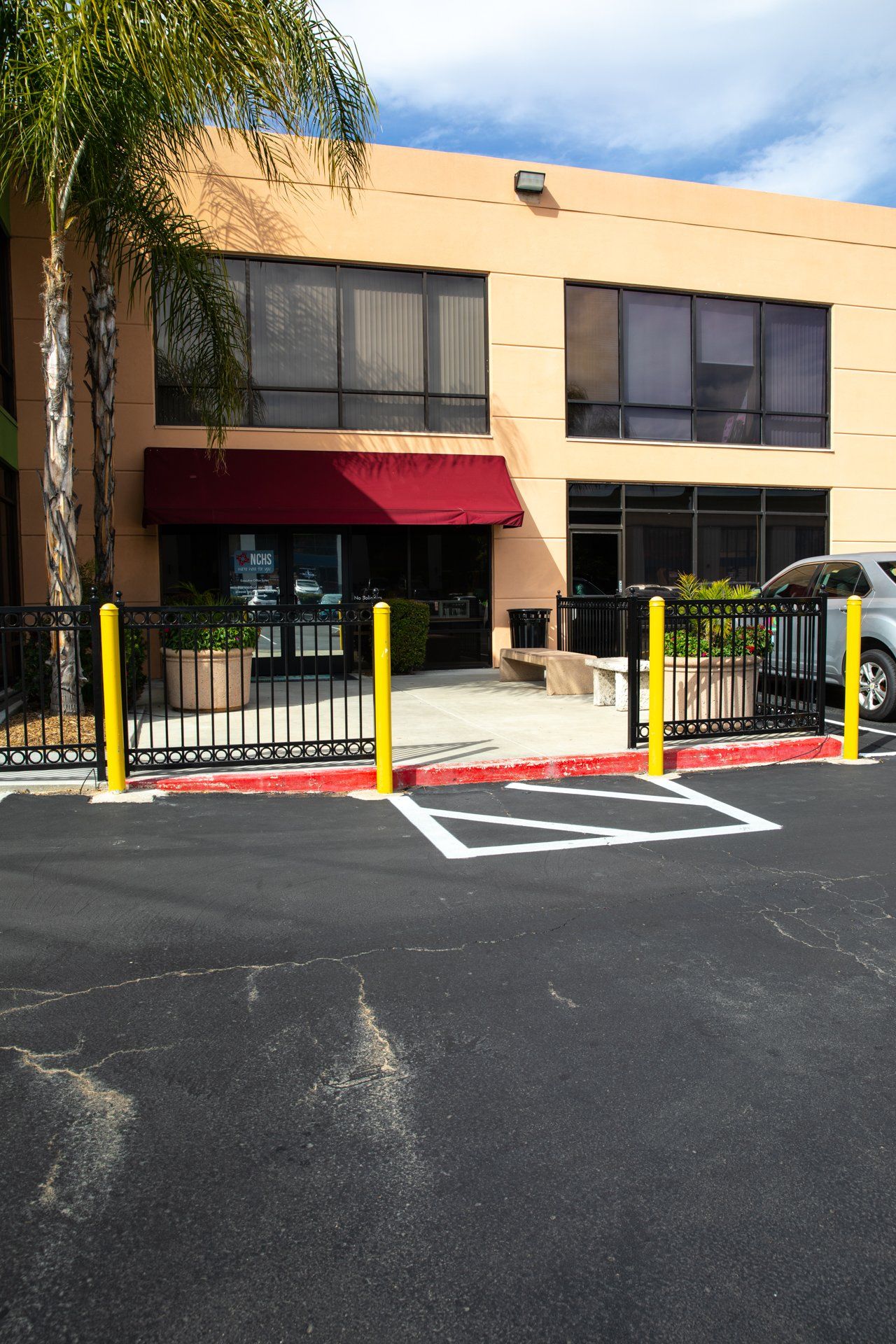 A building with a red awning is behind a parking lot