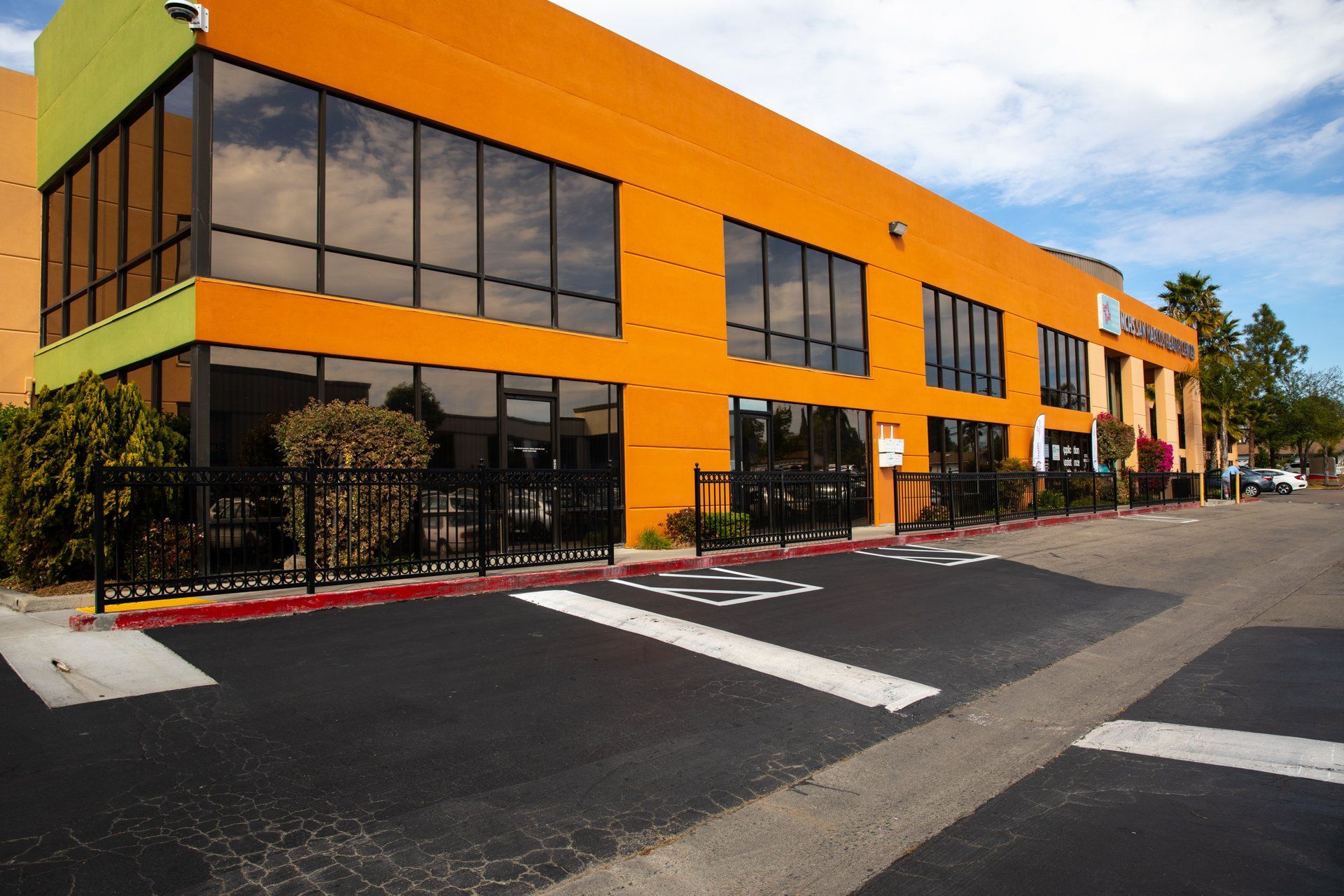 A large orange building with a lot of windows and a parking lot in front of it