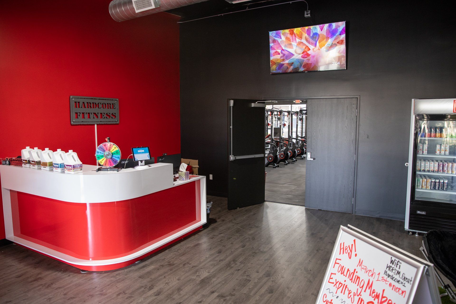 A red and white reception desk in a gym with a tv above it.