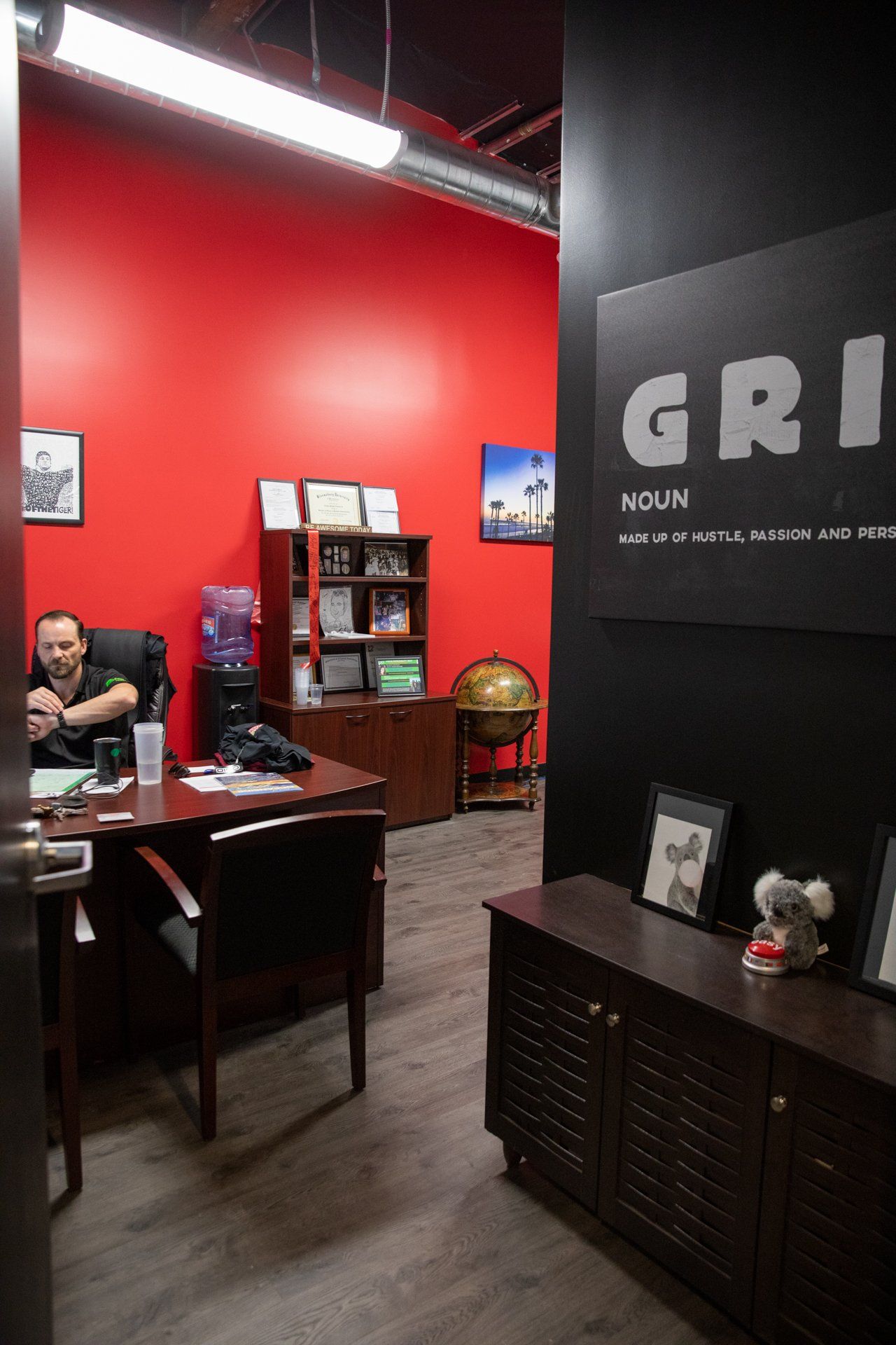 A man is sitting at a desk in a room with red walls.
