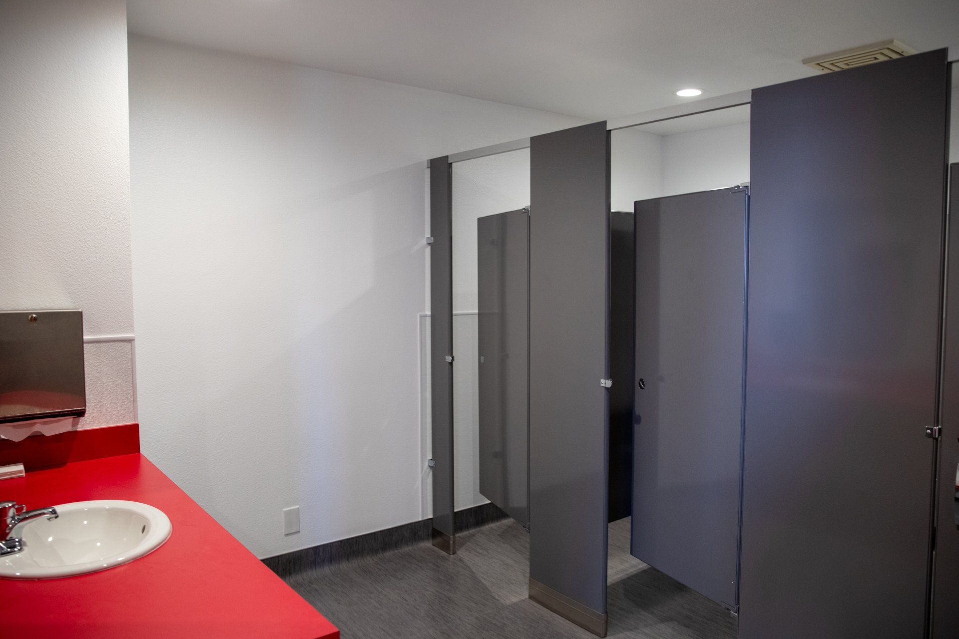 A bathroom with a red counter top and a sink.