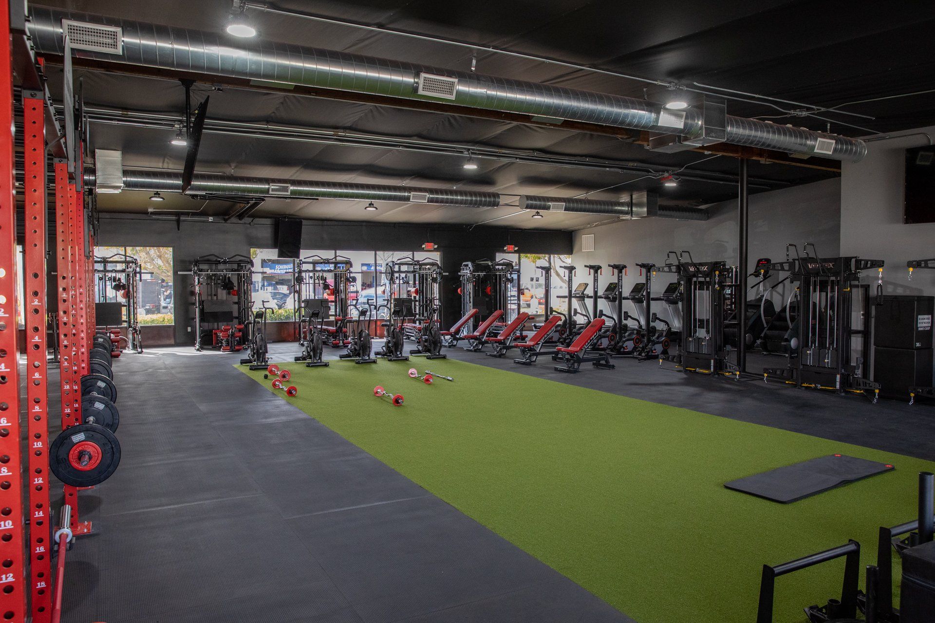 A large gym with a lot of equipment and a green carpet.