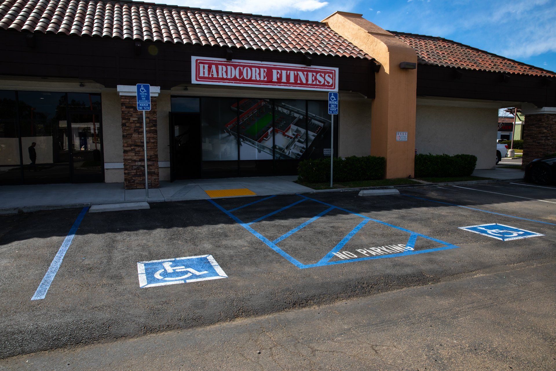 A handicapped parking spot in front of a building that says hardcore fitness