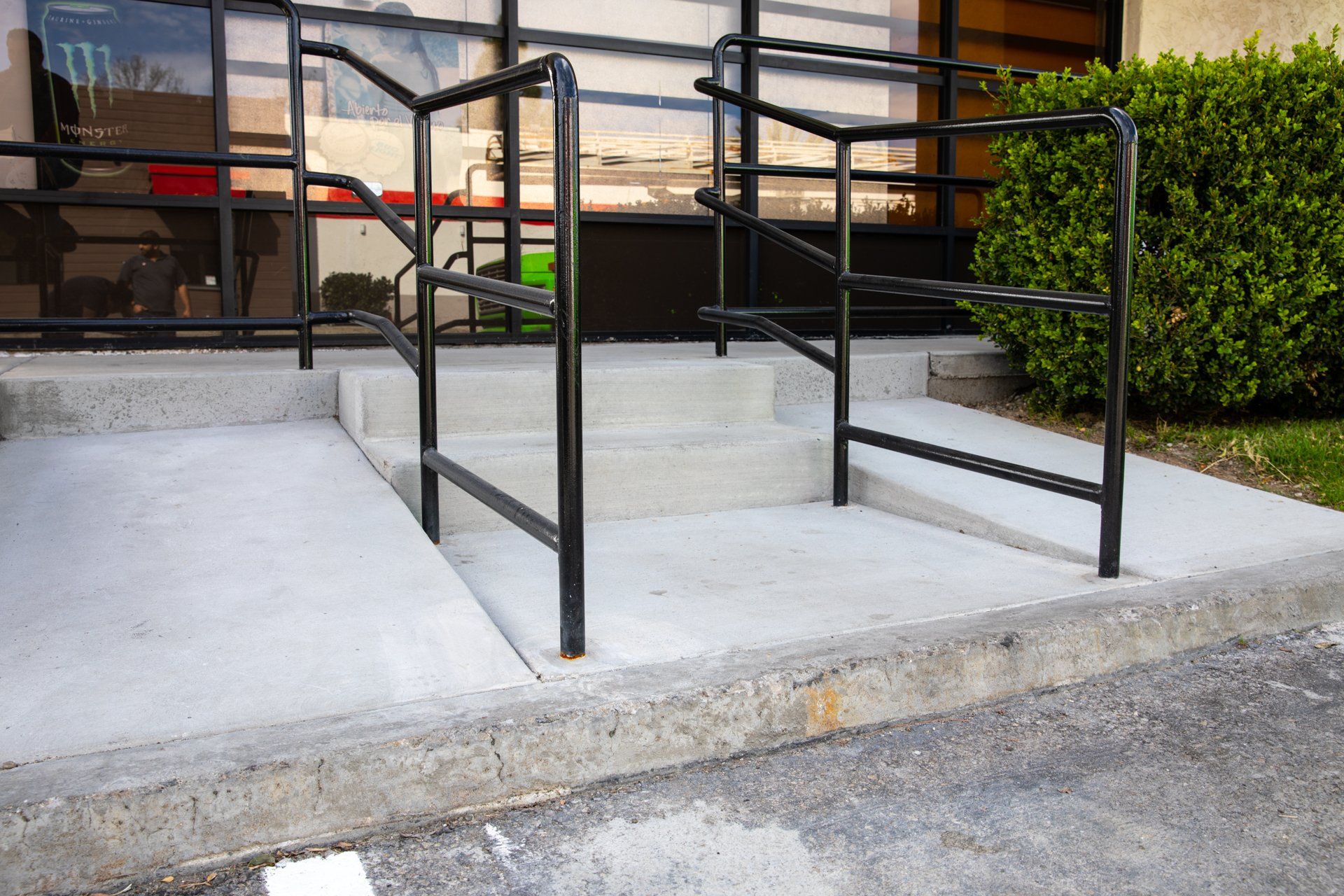 A concrete ramp with a black railing leading to a building