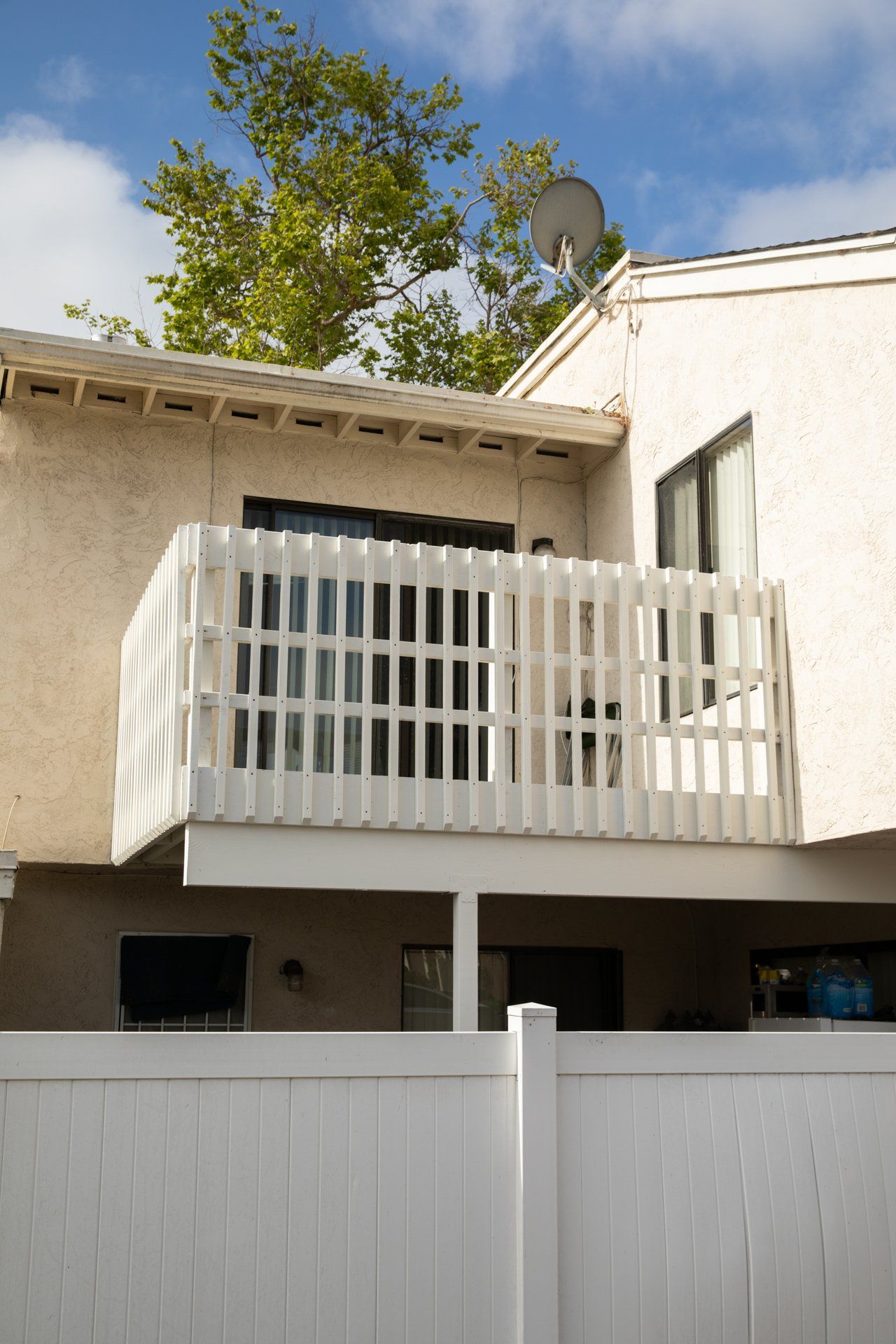A white fence surrounds a house with a balcony