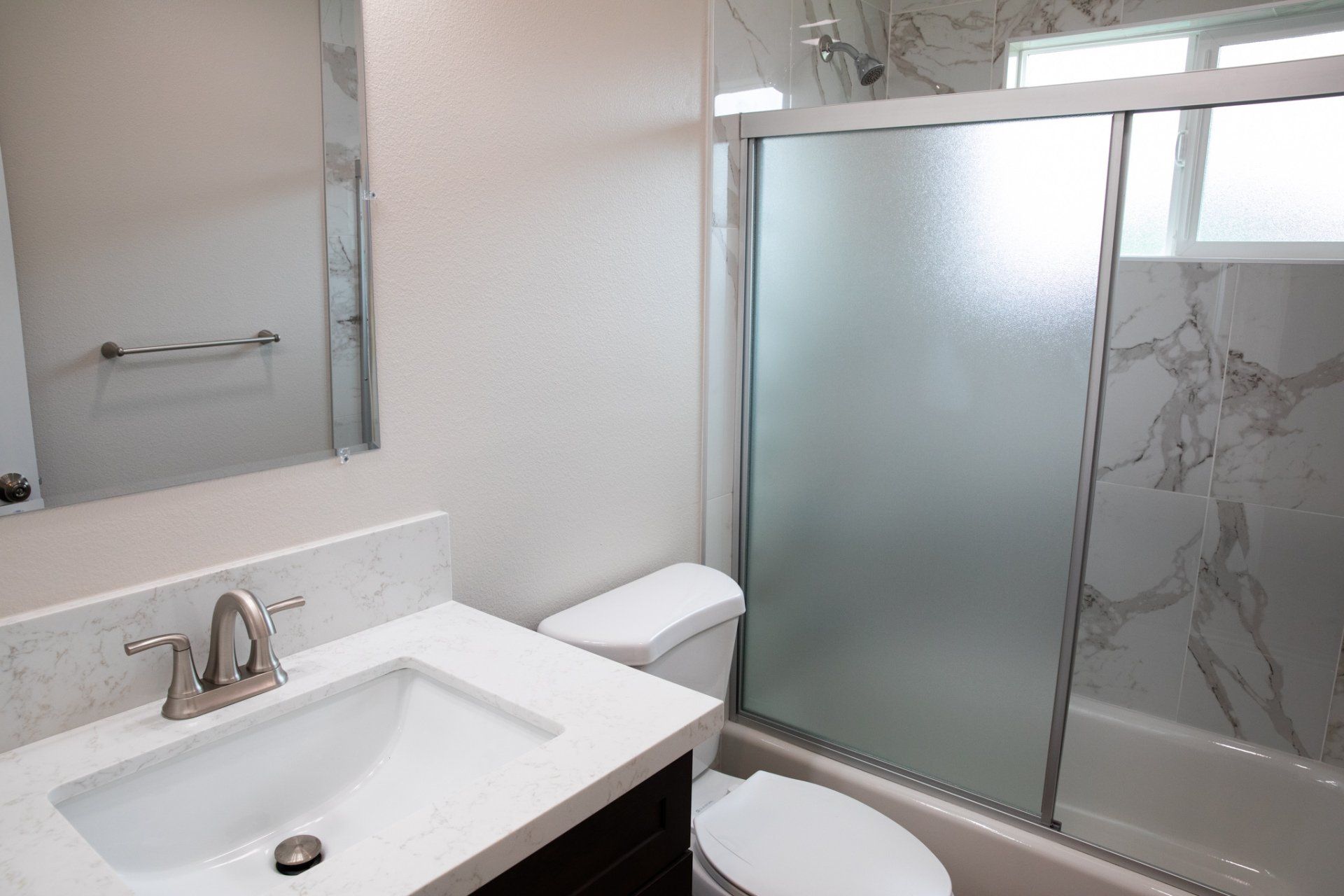 A bathroom with a toilet a sink and a sliding glass shower door