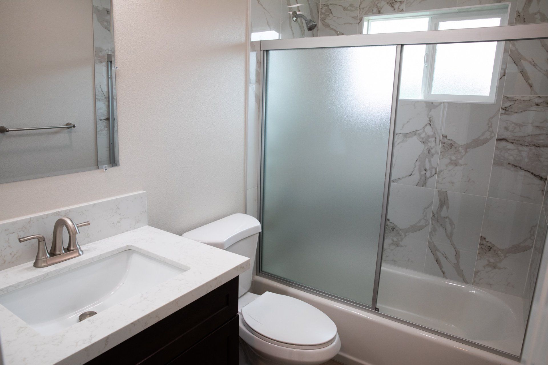 A bathroom with a toilet a sink and a sliding glass shower door