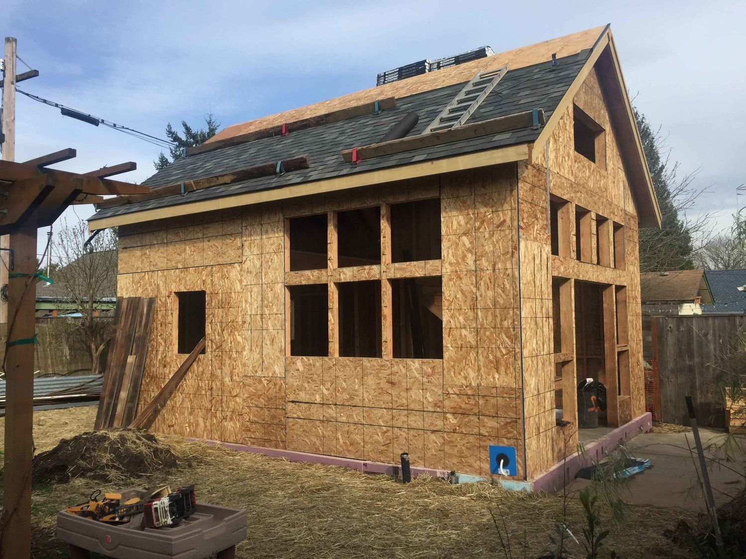 A small wooden house is being built in a backyard.
