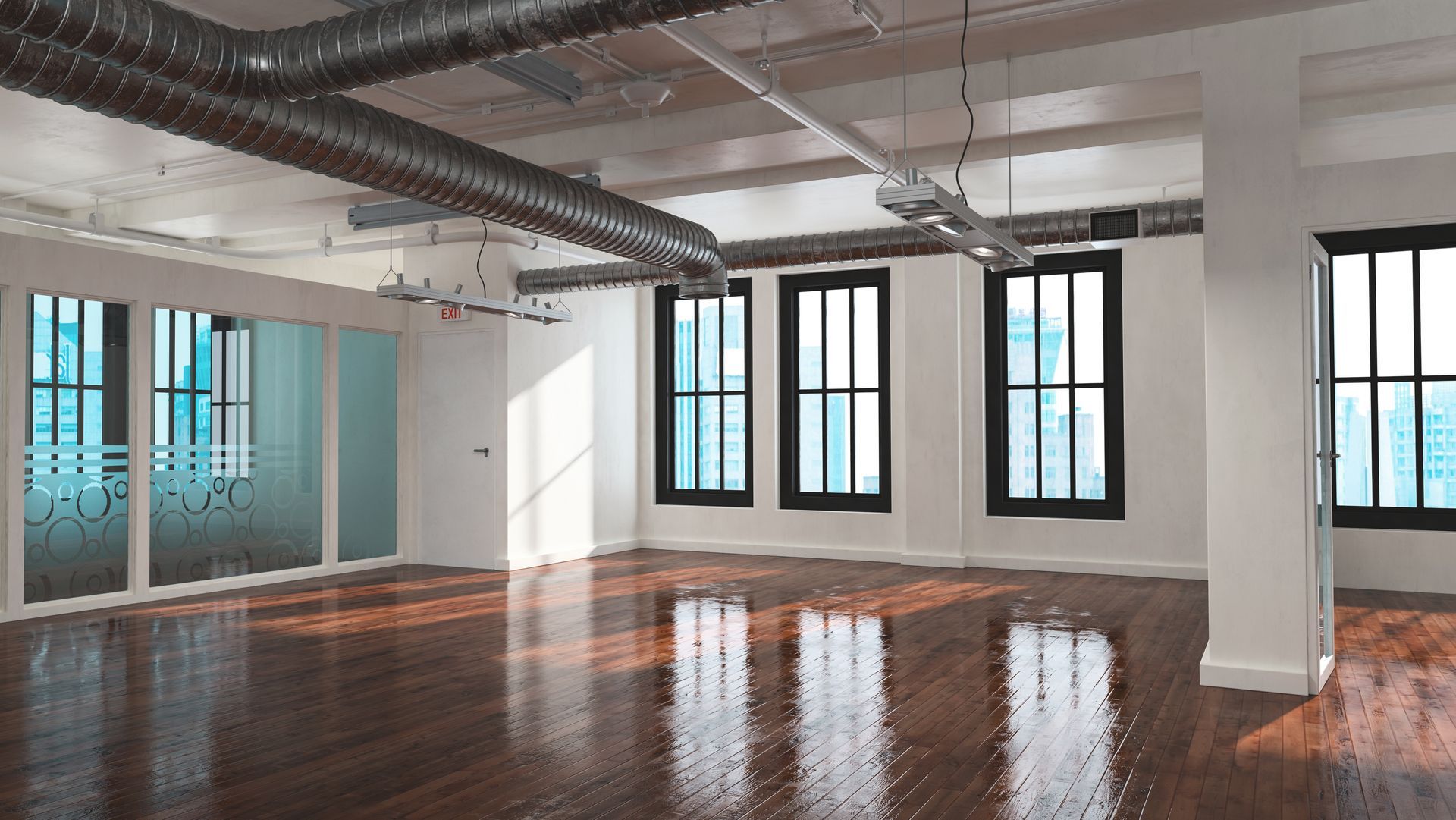A large empty room with hardwood floors and lots of windows.