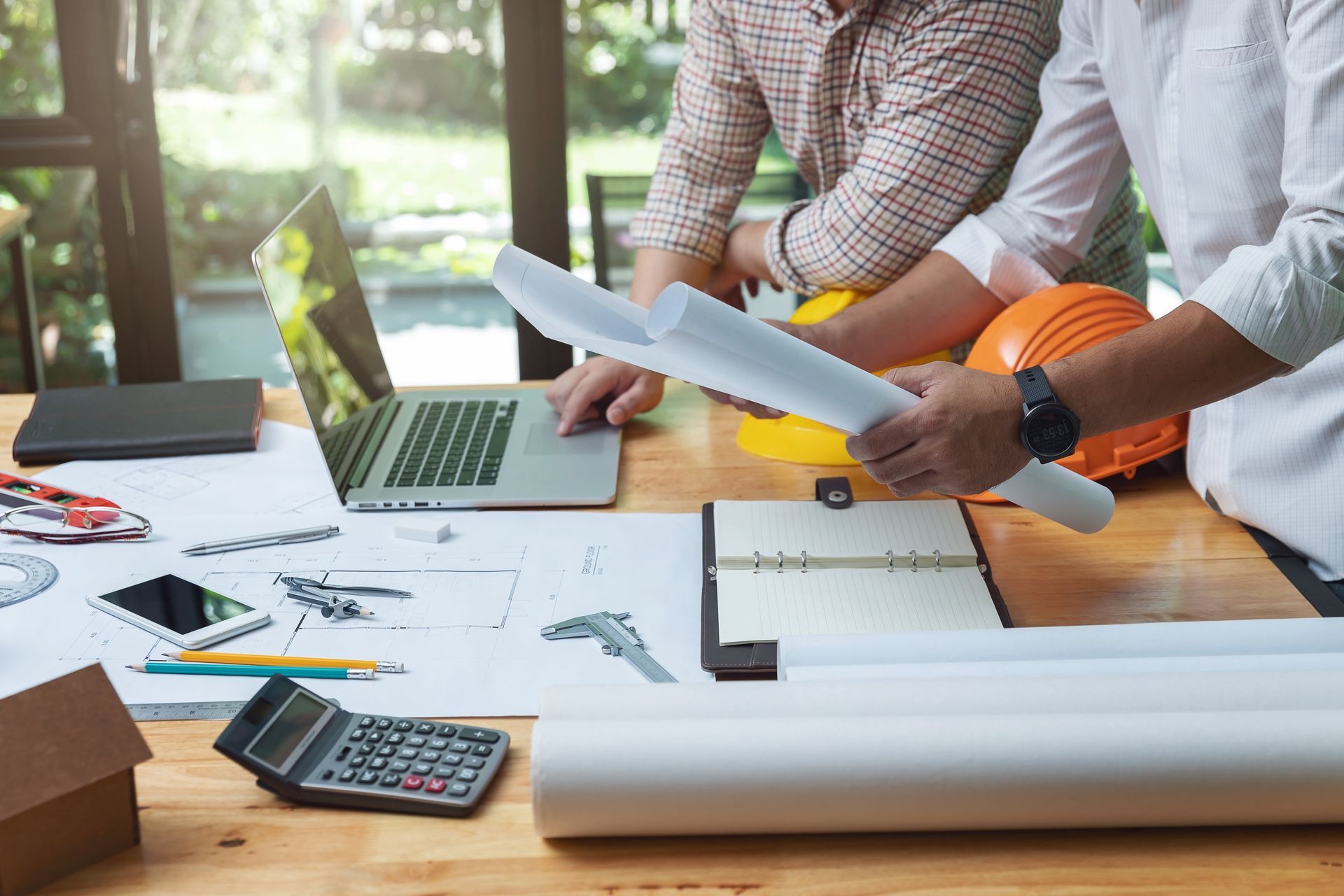 A group of men are sitting at a table looking at papers and a laptop.