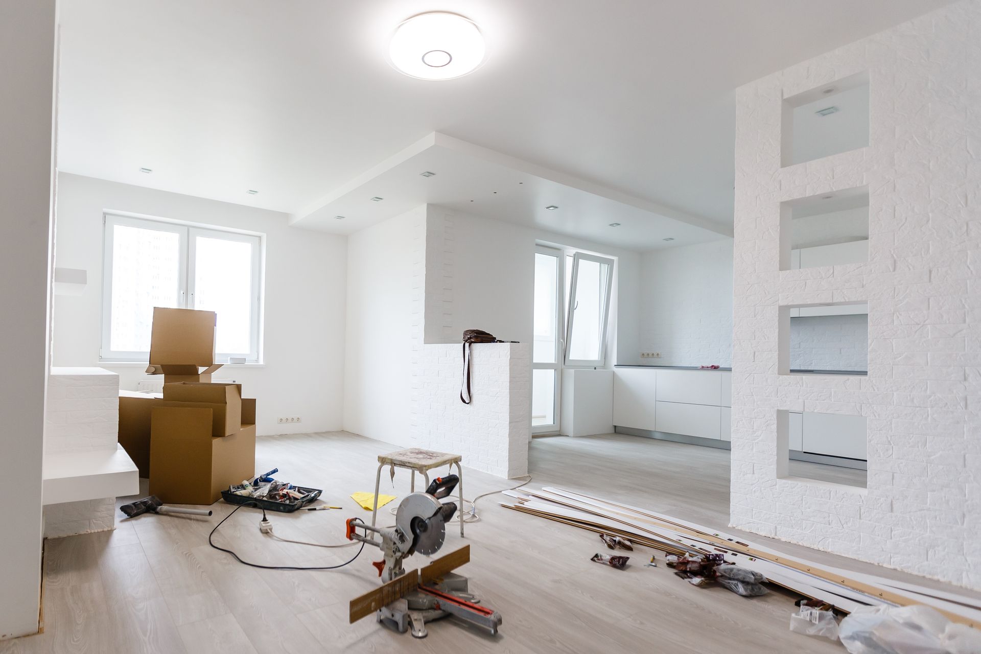 A living room under construction with boxes and tools on the floor.