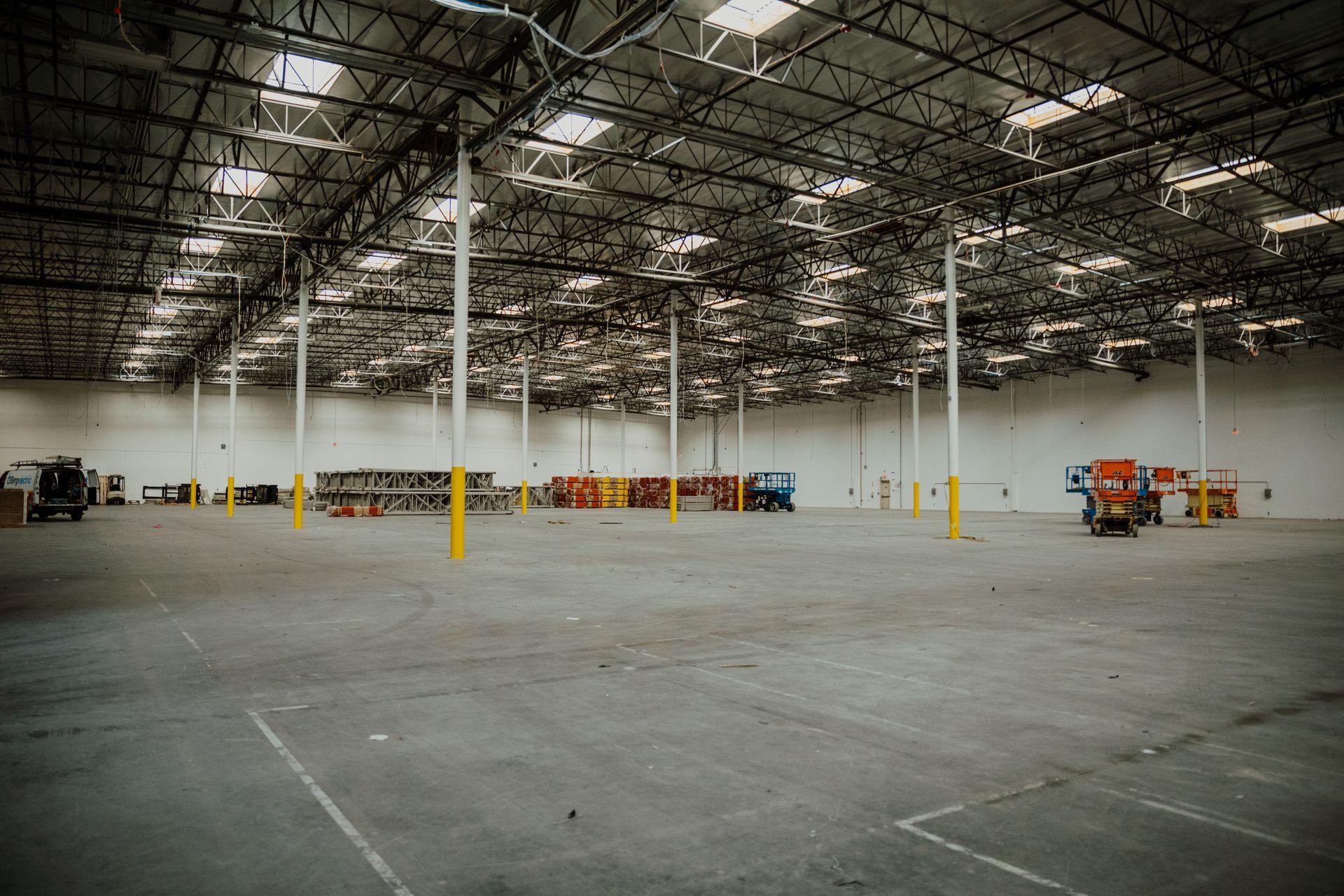A large empty warehouse with a lot of lights on the ceiling.