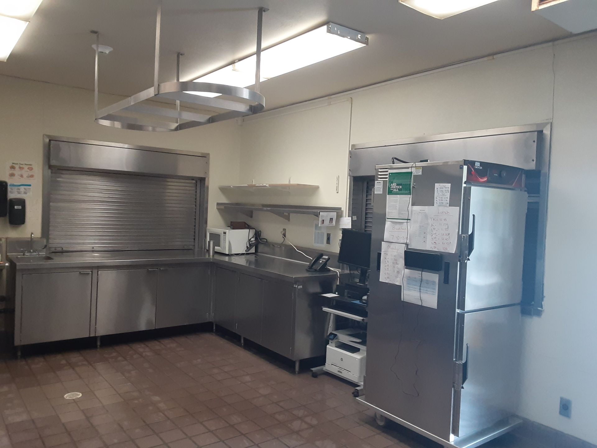 A kitchen with stainless steel appliances and a green exit sign on the wall