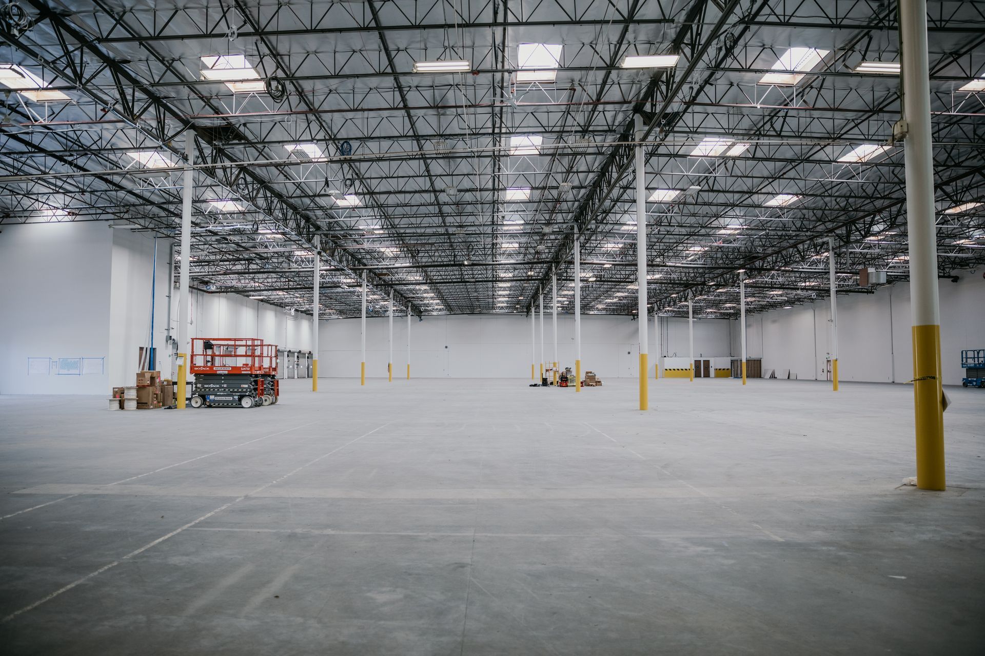 A large empty warehouse with a lot of lights on the ceiling.