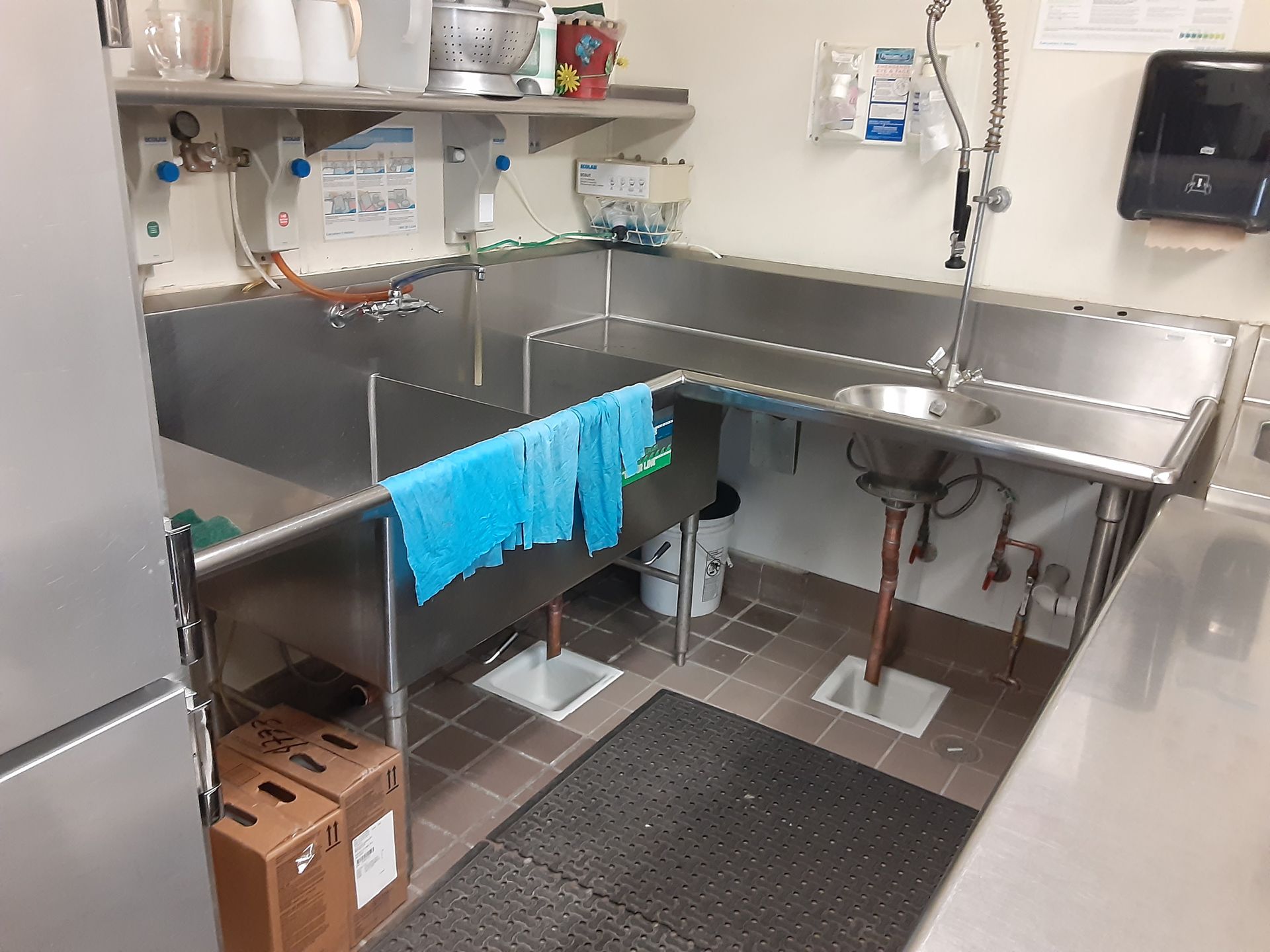 A kitchen with a stainless steel sink and a towel hanging on the wall.