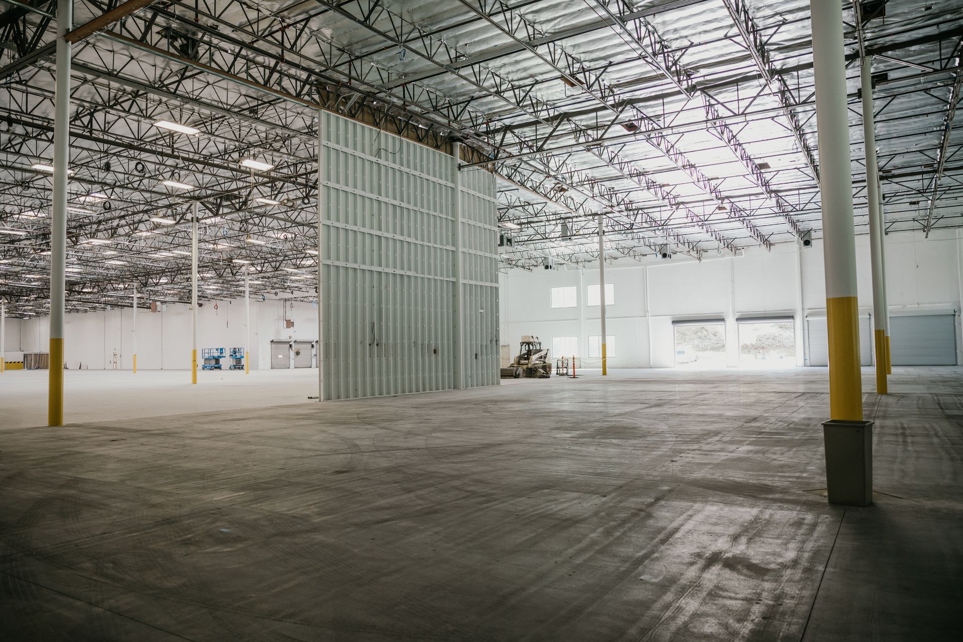 An empty warehouse with a forklift parked in the middle of it.