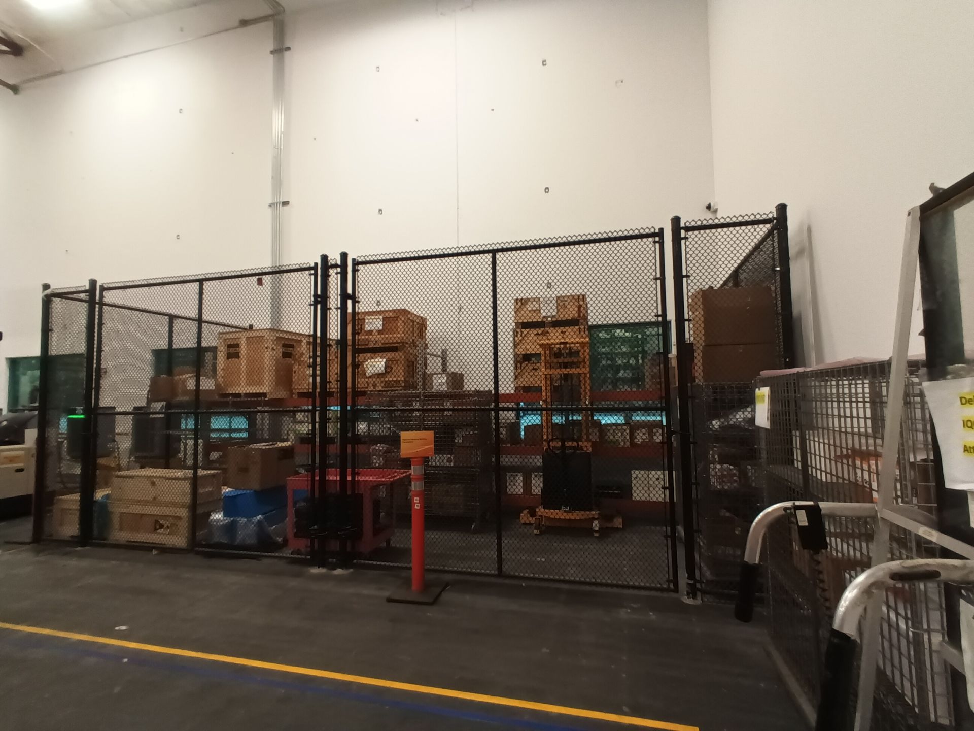 A warehouse with a chain link fence and lots of boxes on shelves.