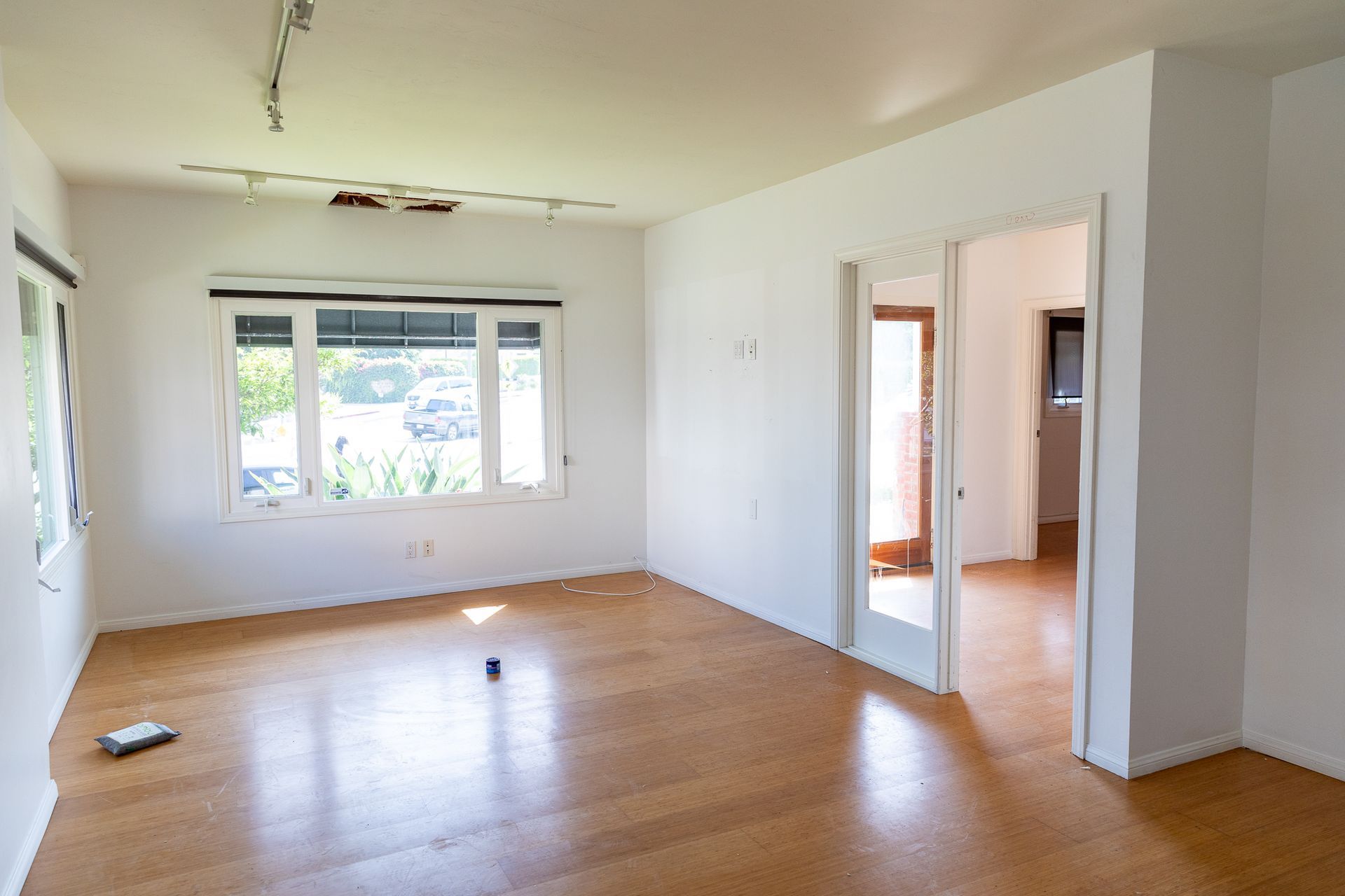 An empty living room with hardwood floors and white walls