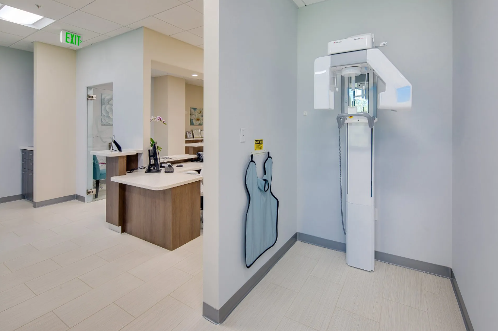 A dental office with a x-ray machine in the middle of the room.