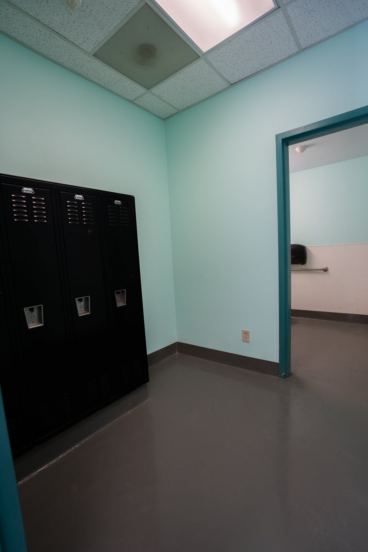 A locker room with blue walls and black lockers