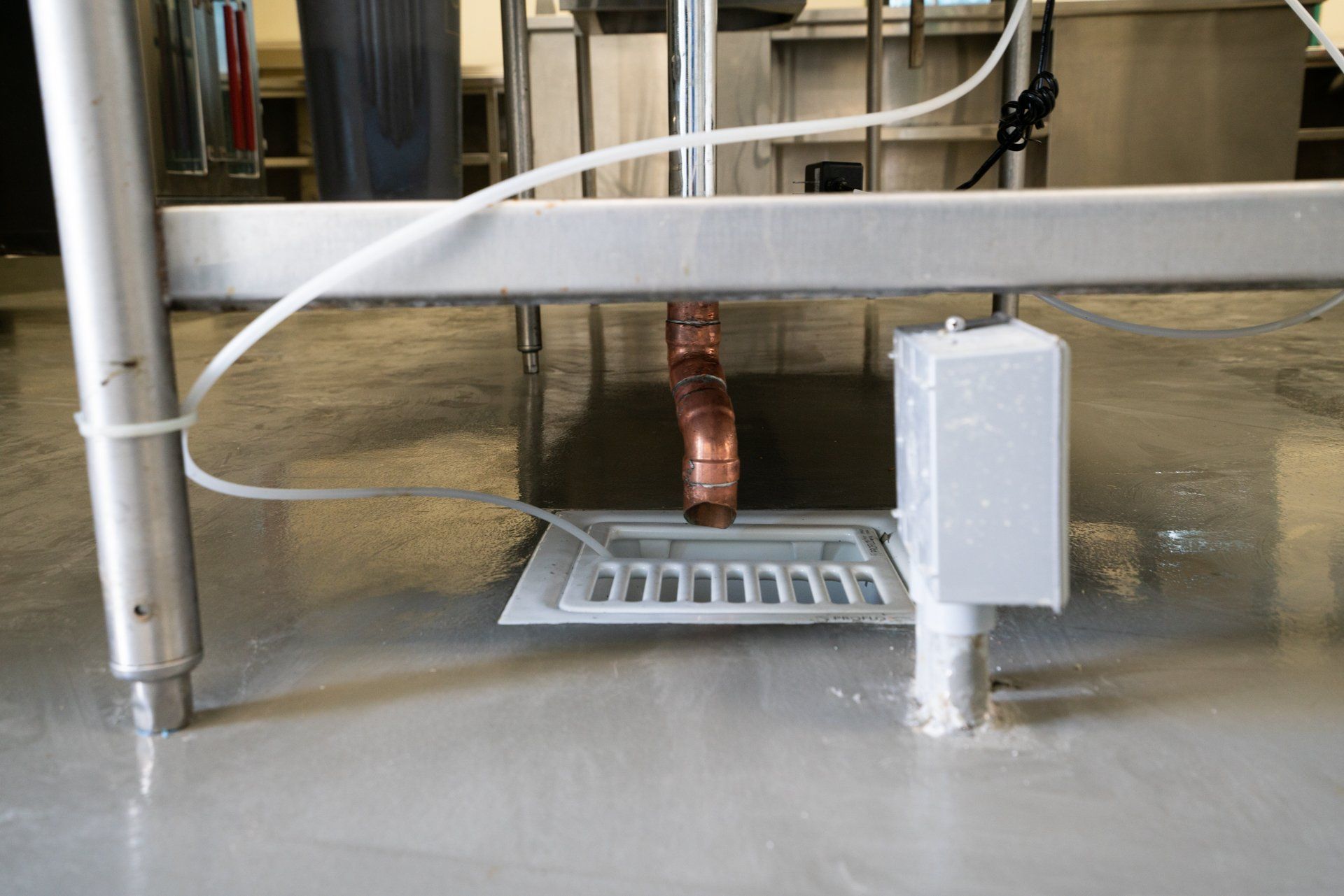 A stainless steel table with a drain underneath it.