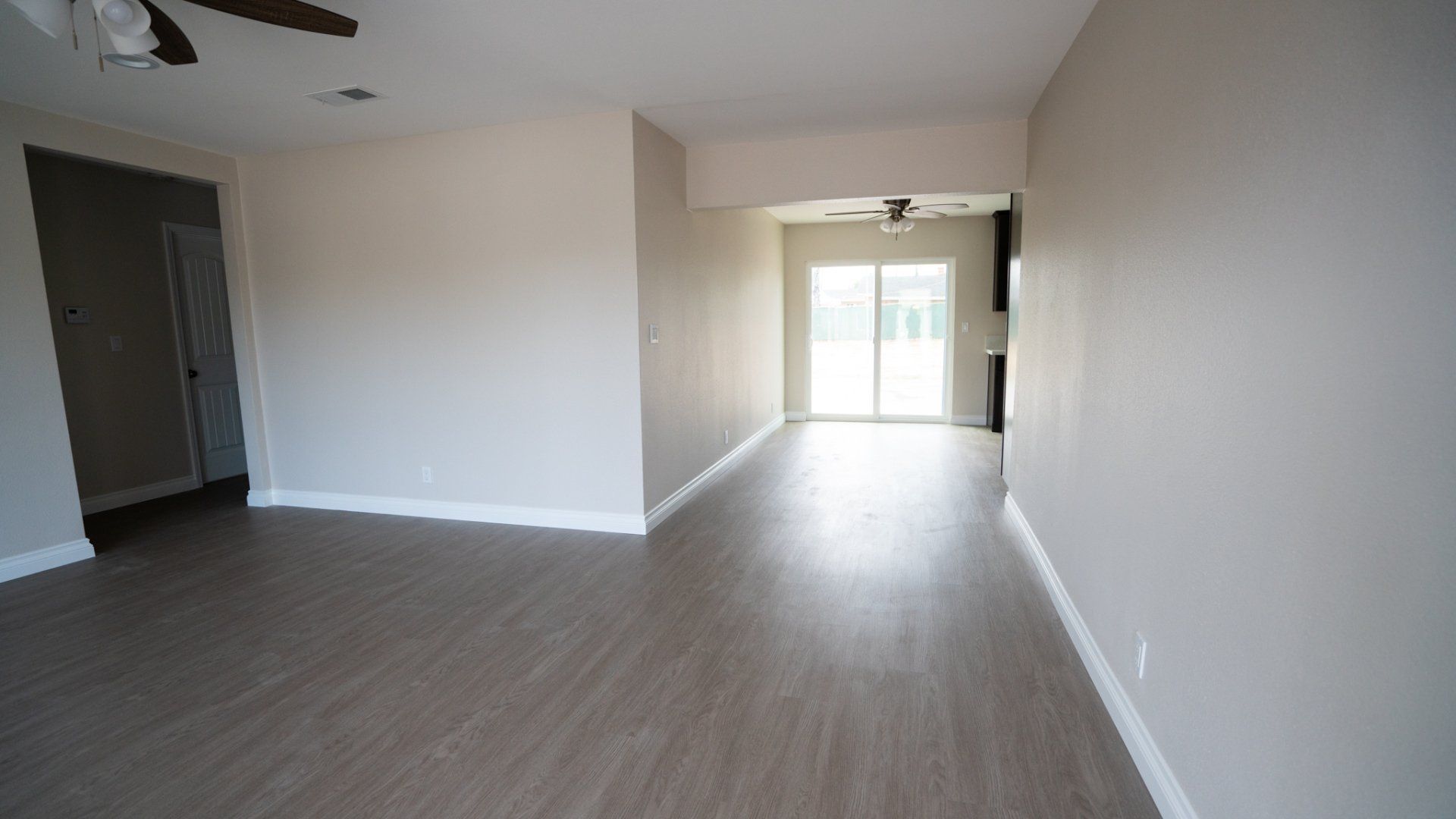 An empty living room with hardwood floors and a ceiling fan