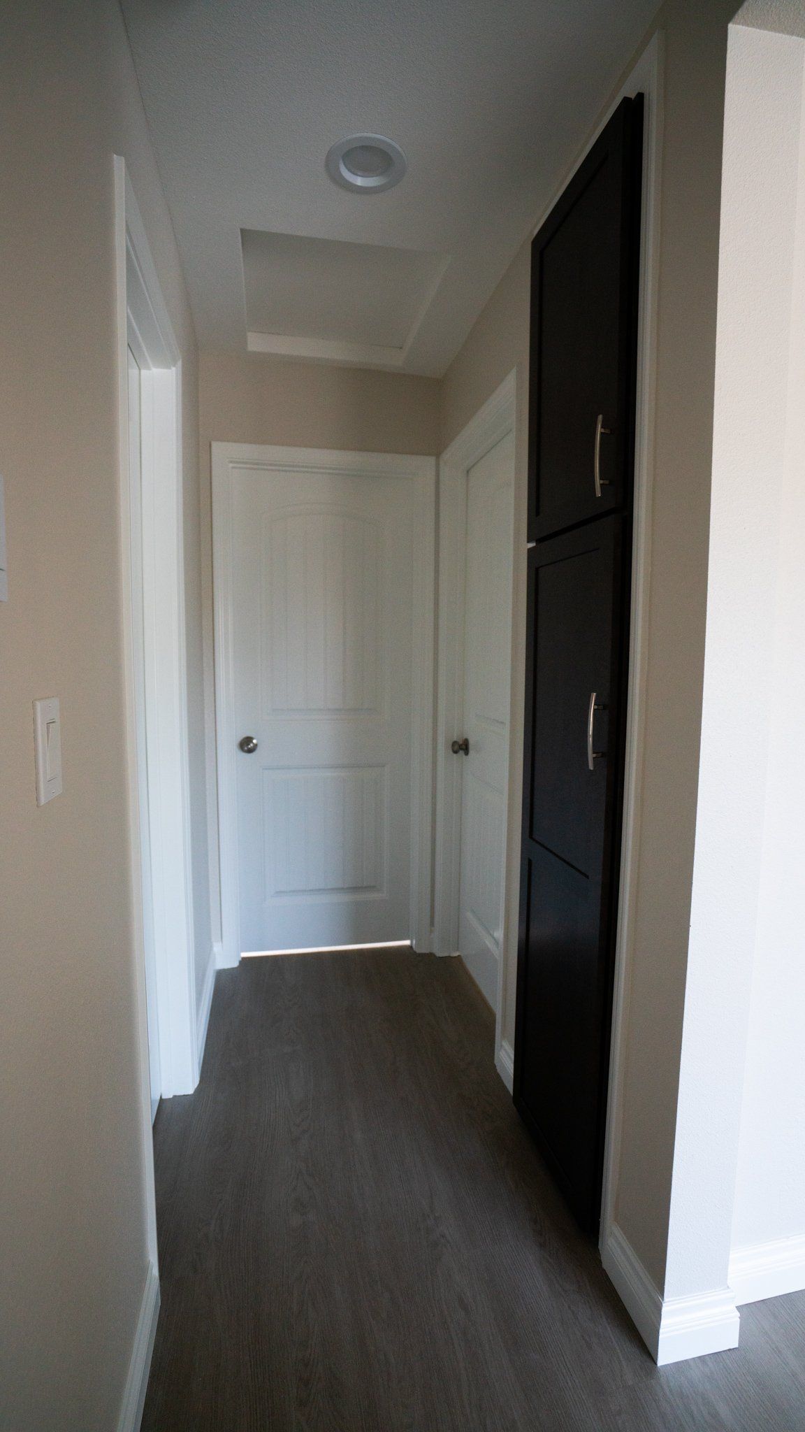 A hallway with a black cabinet and a white door
