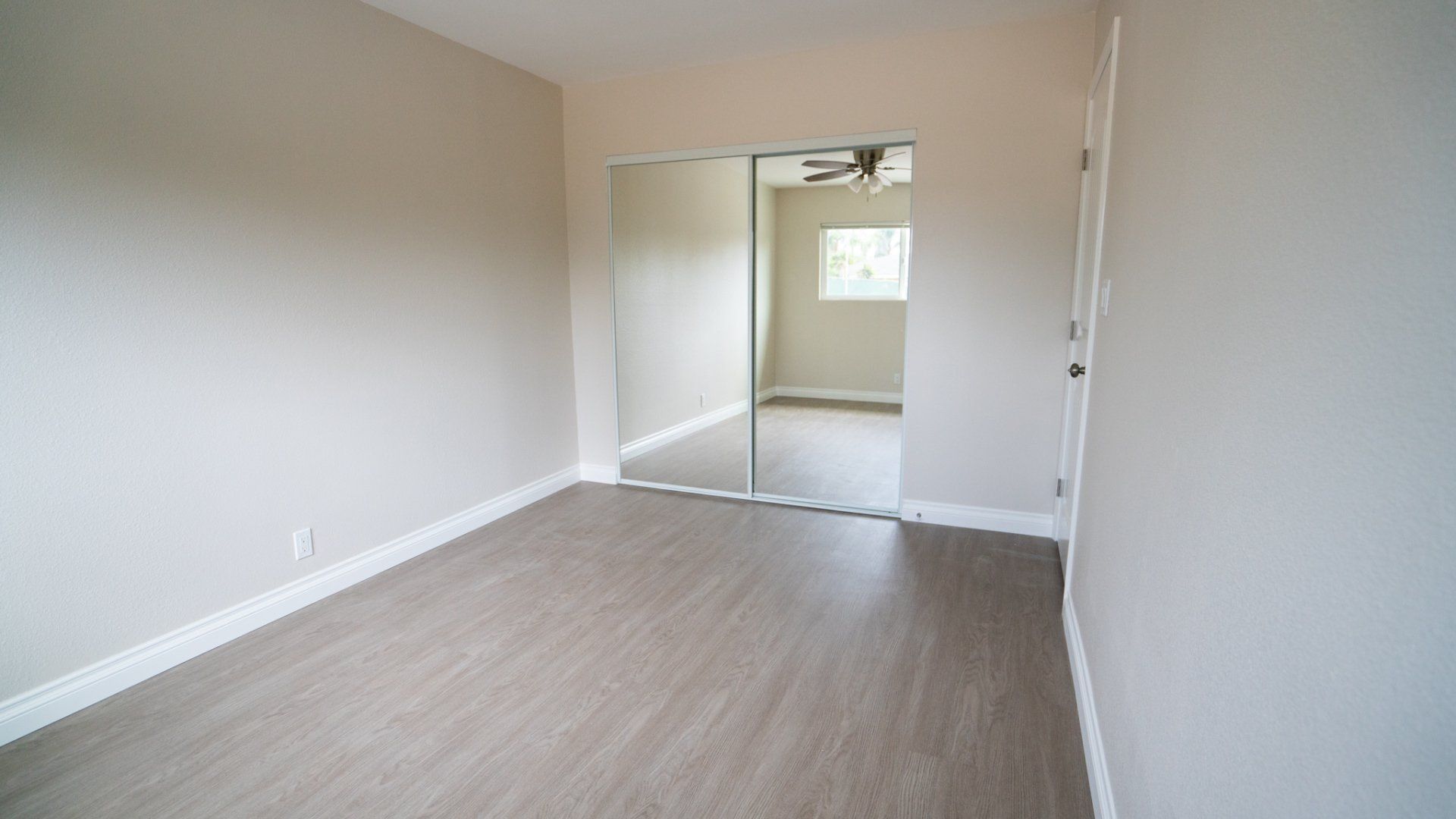 An empty room with hardwood floors and sliding glass doors
