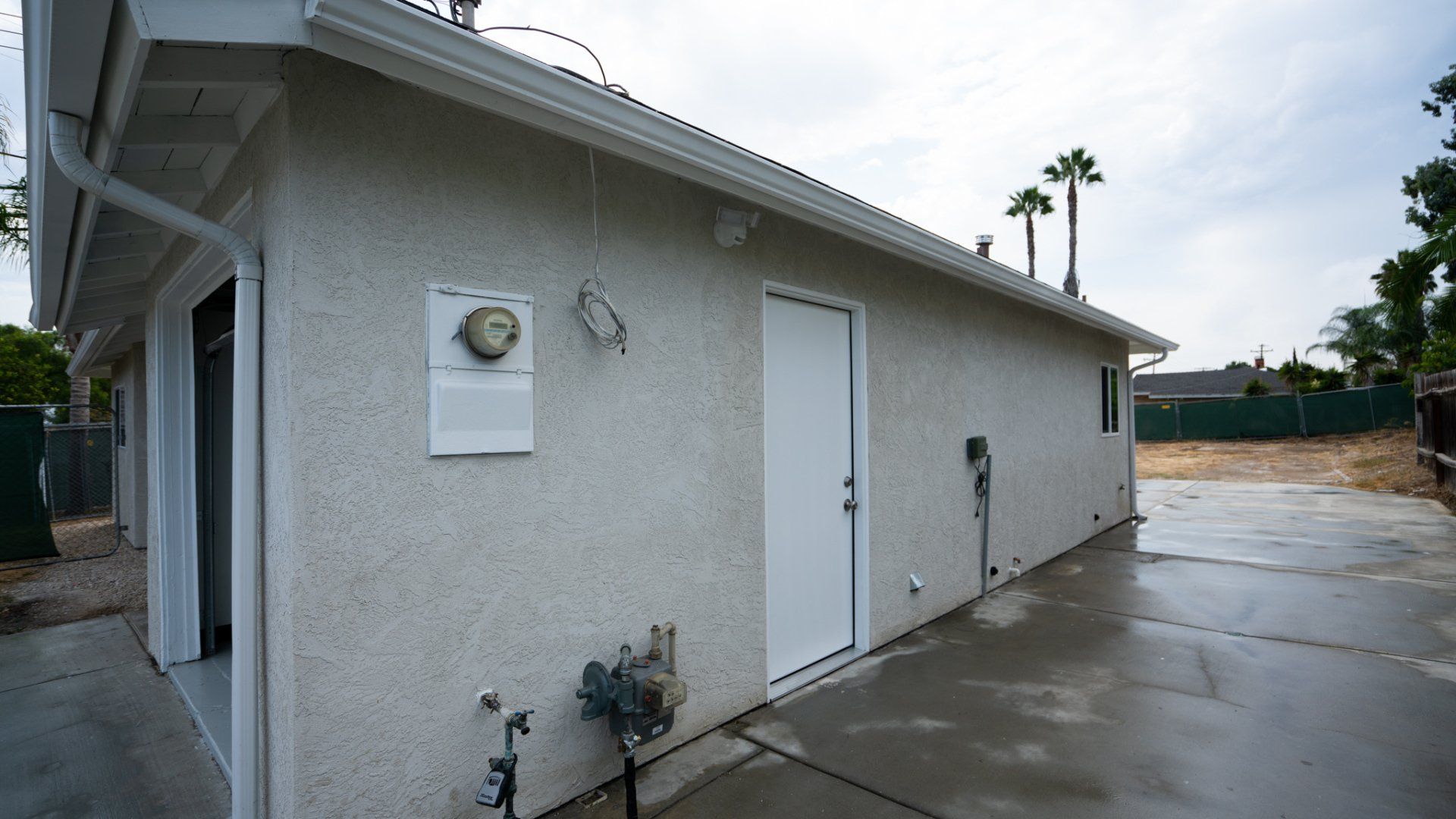 A white building with a door and a meter on the side