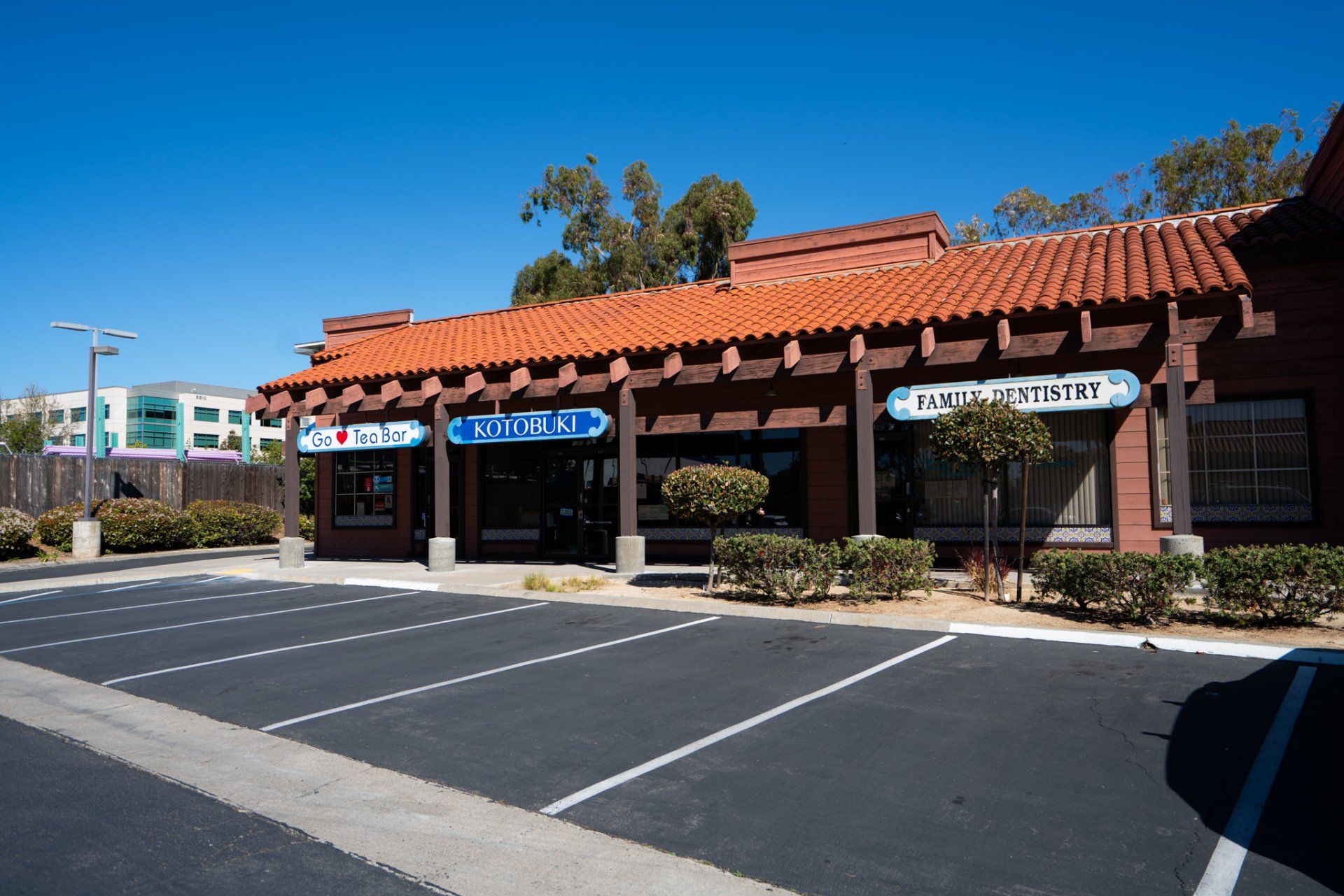 A brick building with a red tile roof and a parking lot in front of it