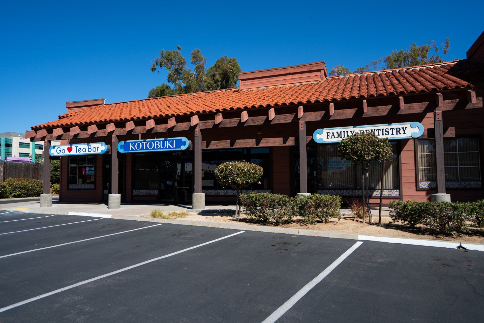 A brick building with a red tile roof and a parking lot in front of it.