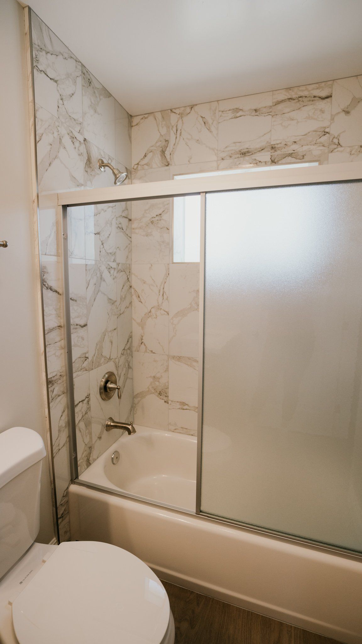 A bathroom with a toilet , tub , shower and sliding glass door.