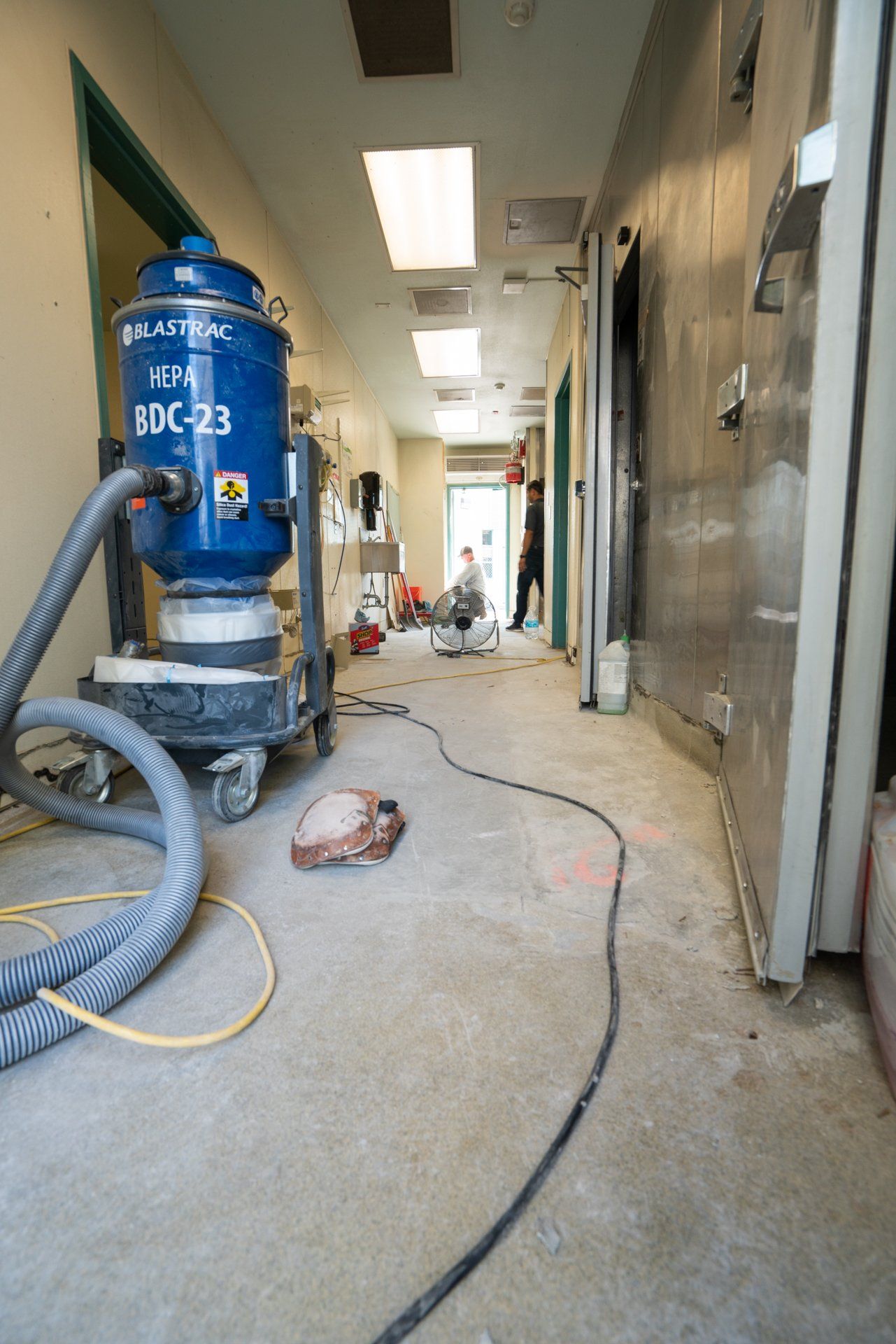 A blue vacuum cleaner is sitting in a hallway.