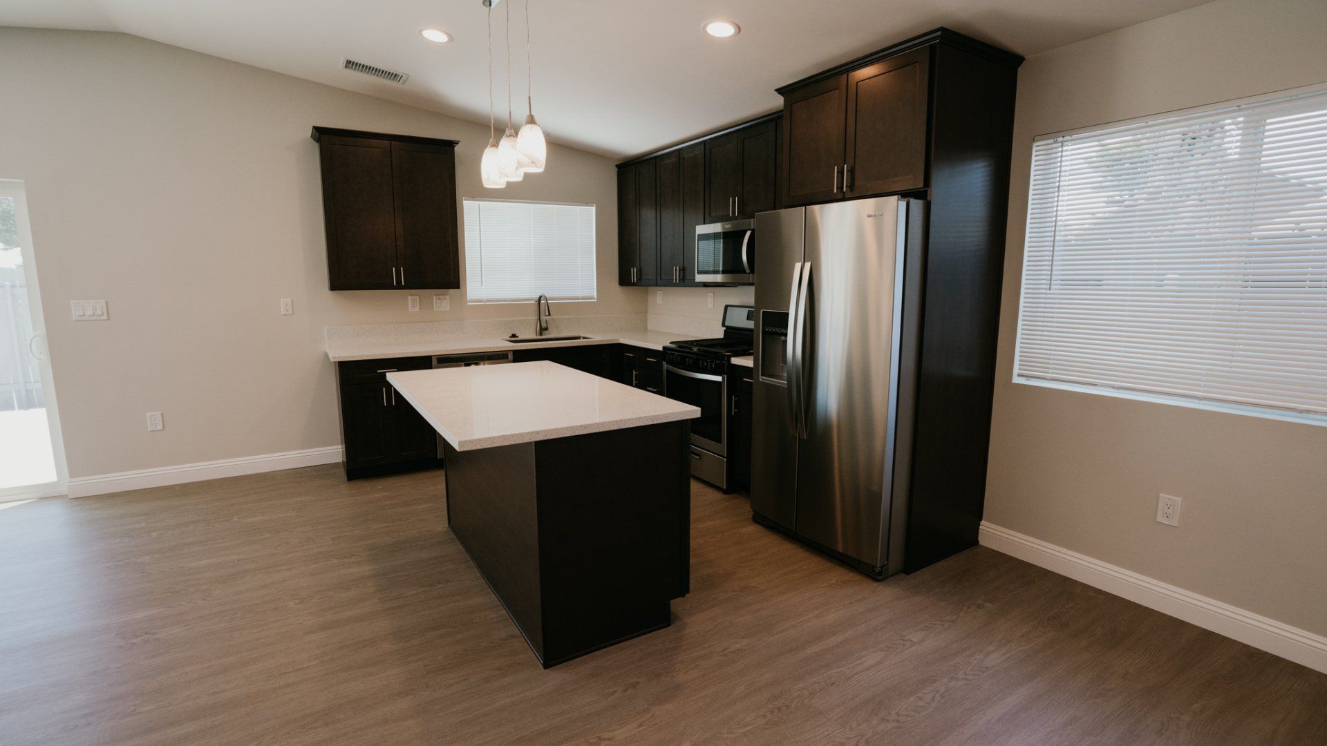 An empty kitchen with stainless steel appliances and a large island.