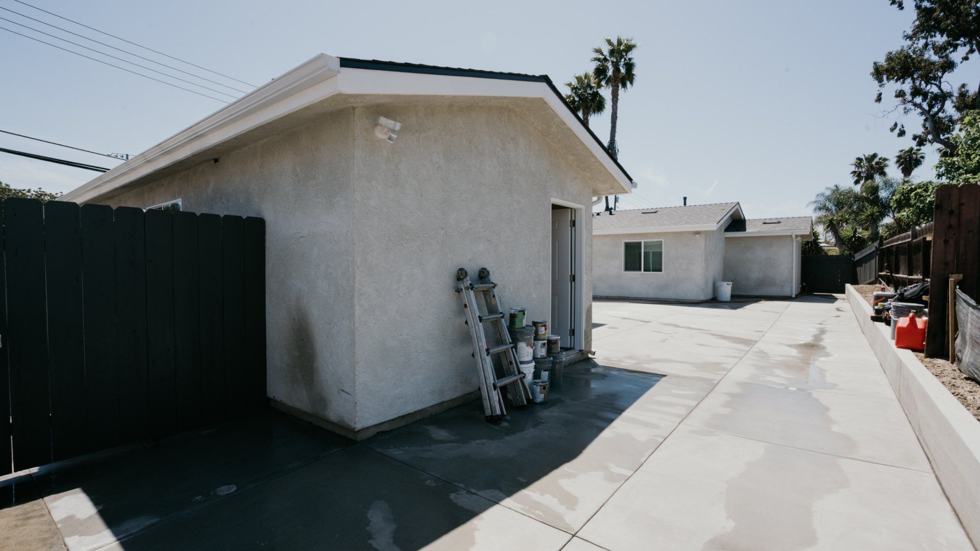 A white house with a black fence and a ladder in front of it