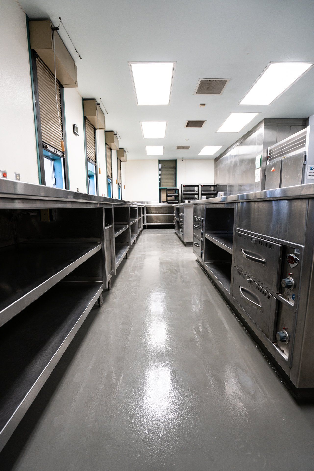An empty kitchen with stainless steel appliances and shelves