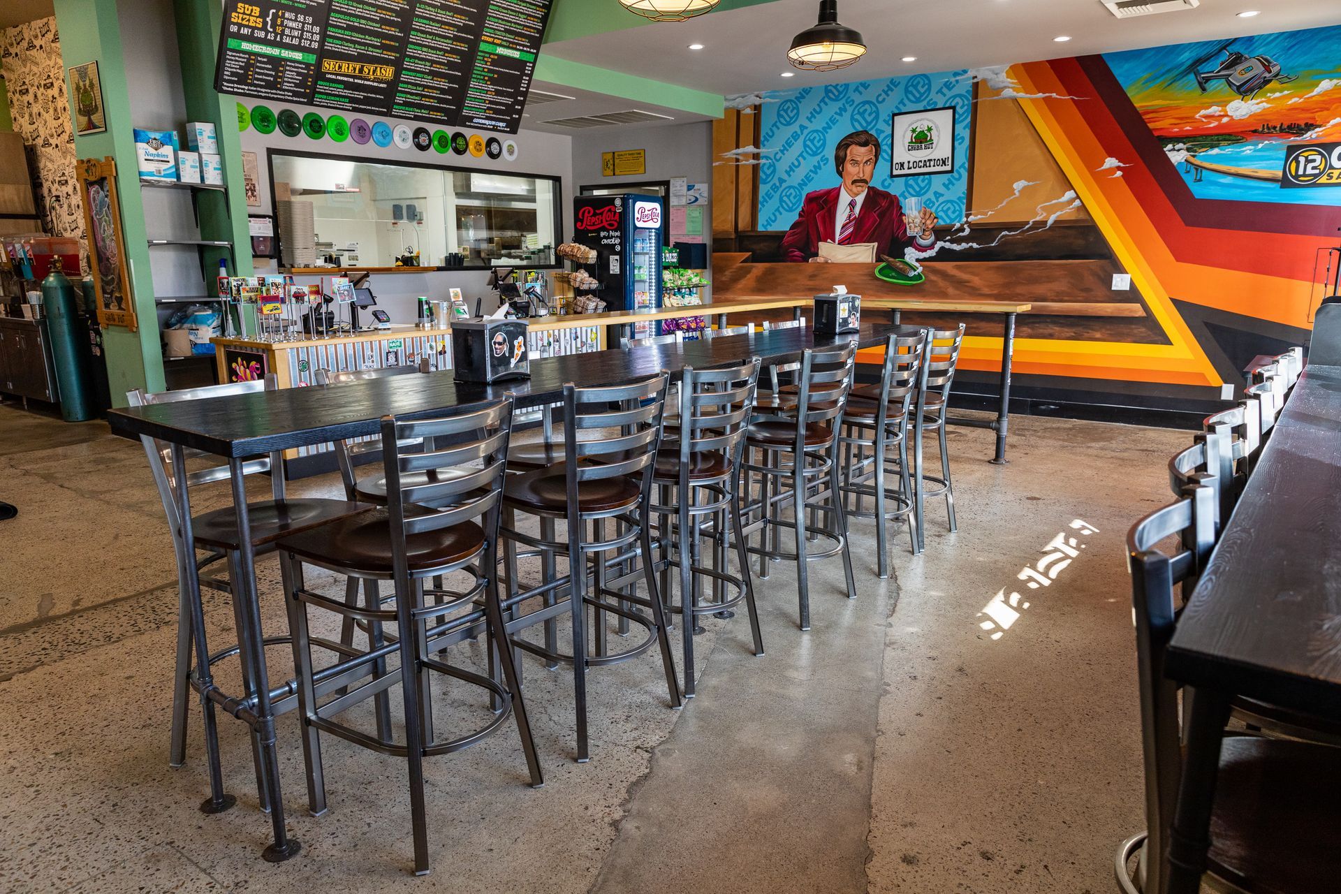 A restaurant with tables and chairs and a mural on the wall.