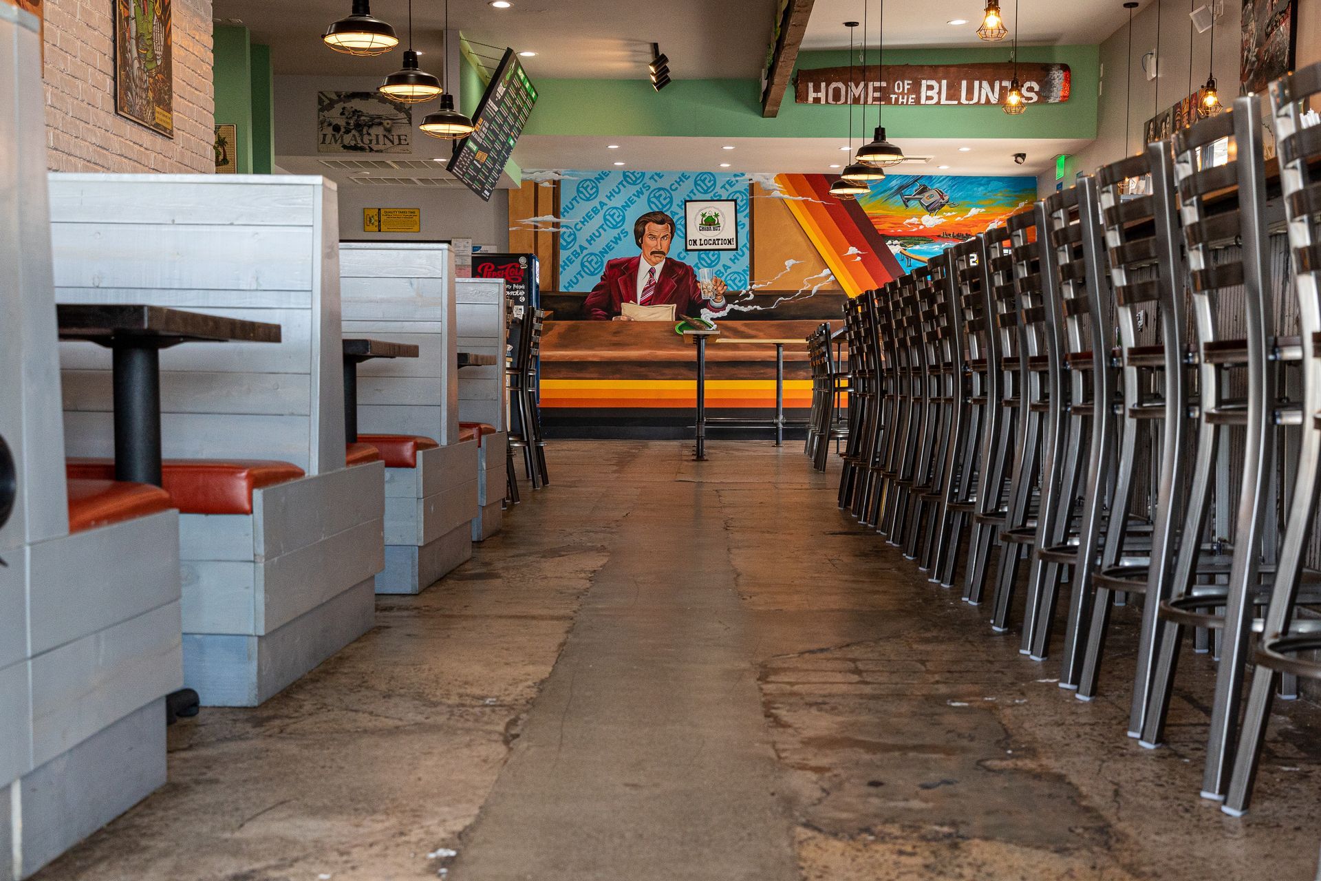 A restaurant with tables and chairs and a painting on the wall.
