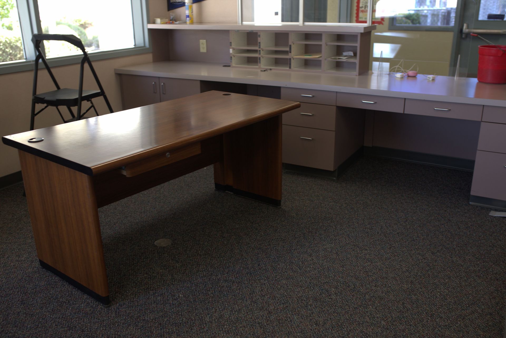 An empty office with a wooden desk and drawers