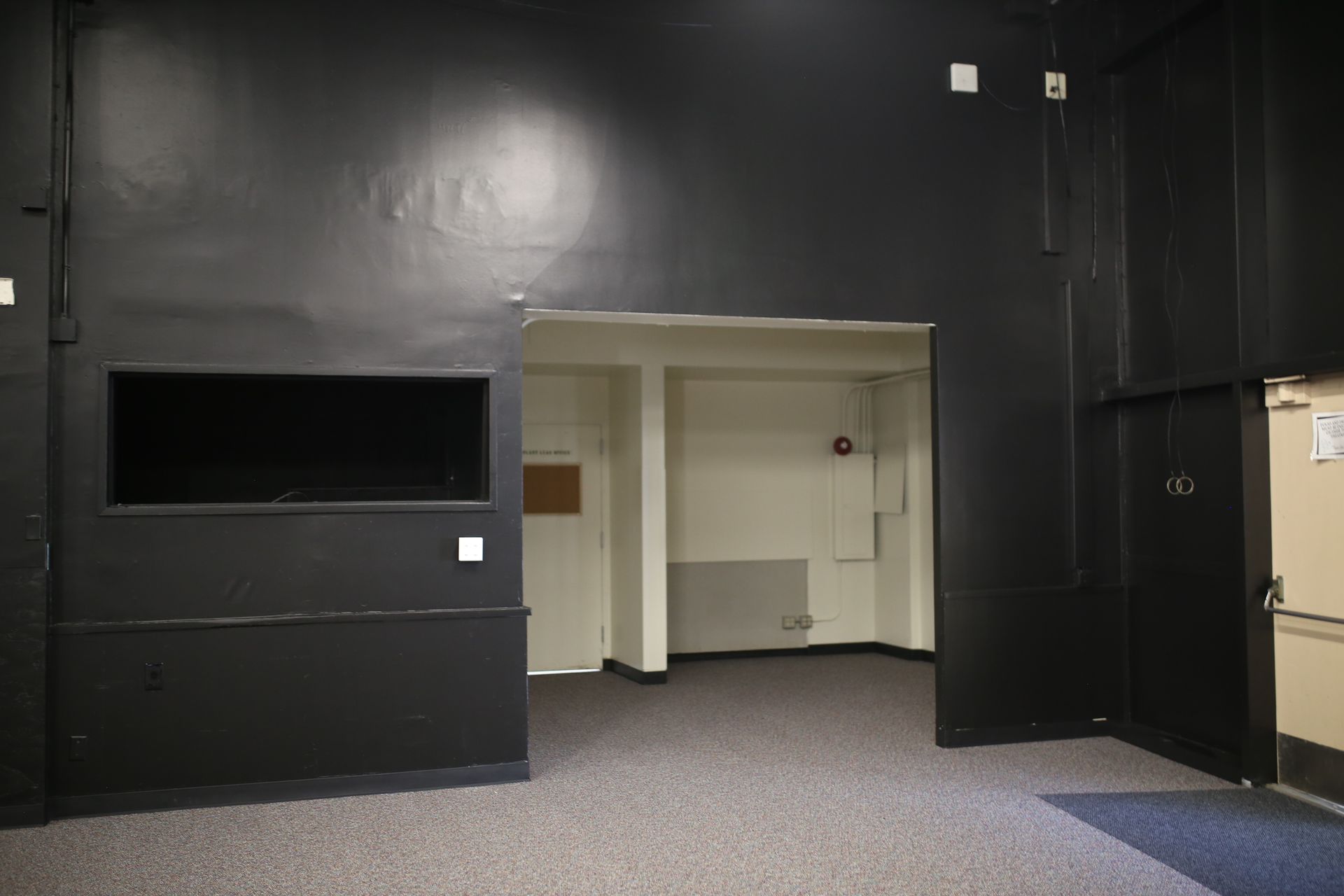 An empty room with a black wall and a door