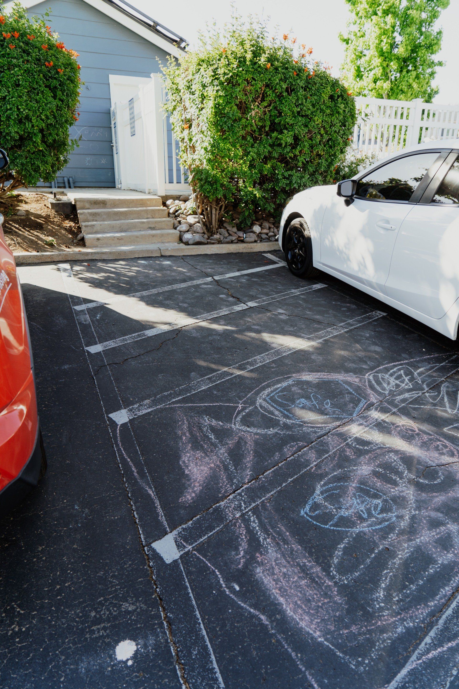 A red car is parked next to a white car in a parking lot