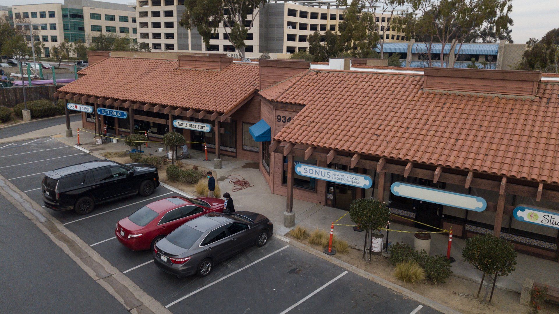 An aerial view of a parking lot with cars parked in front of a building.