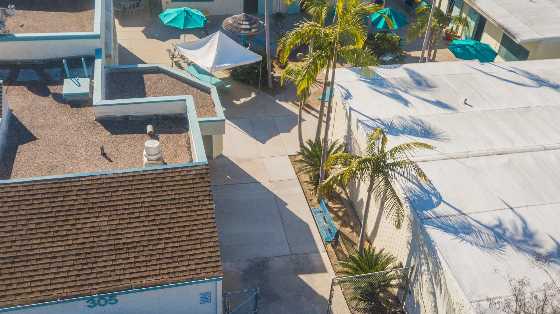 An aerial view of a building with palm trees and umbrellas