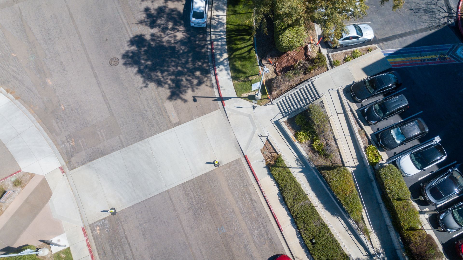 An aerial view of an intersection with cars parked on the side of the road.
