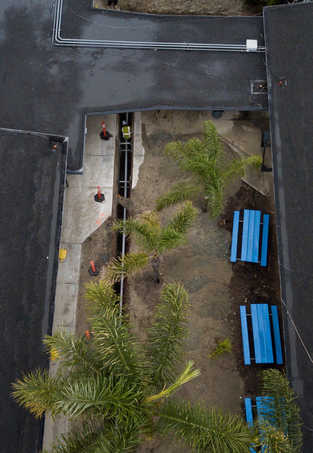An aerial view of a building with blue pipes in the dirt