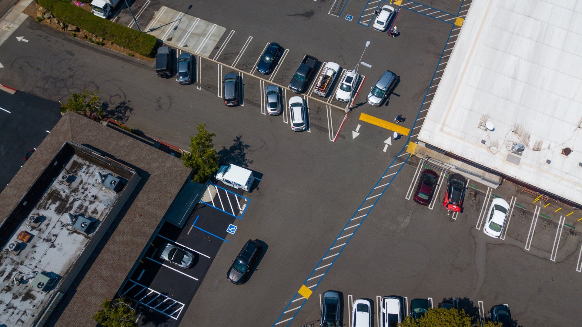 An aerial view of a parking lot with a white building in the background